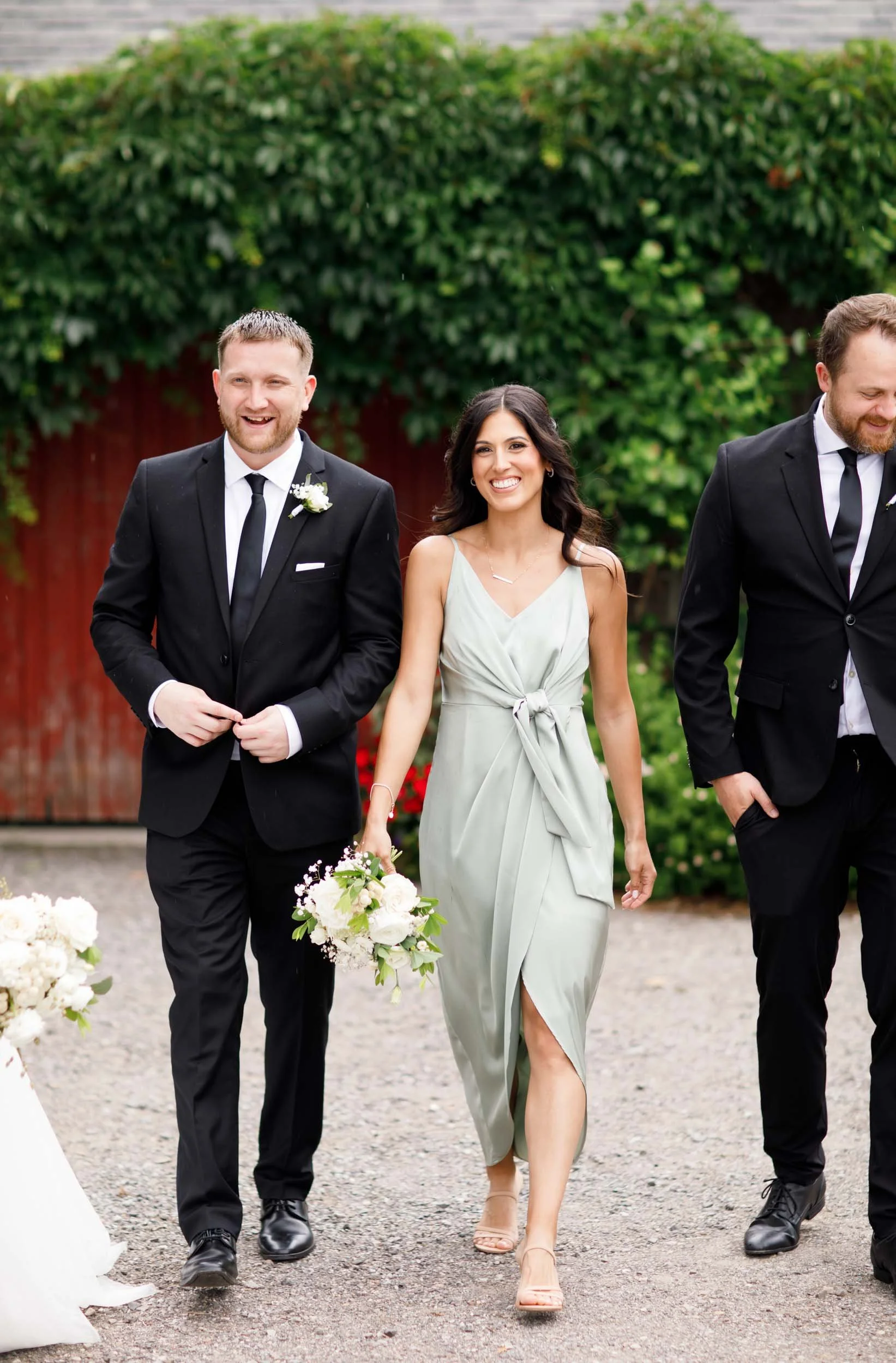 Bridesmaid walking with groomsmen during wedding portraits at Cambium Farms in Alton, Ontario