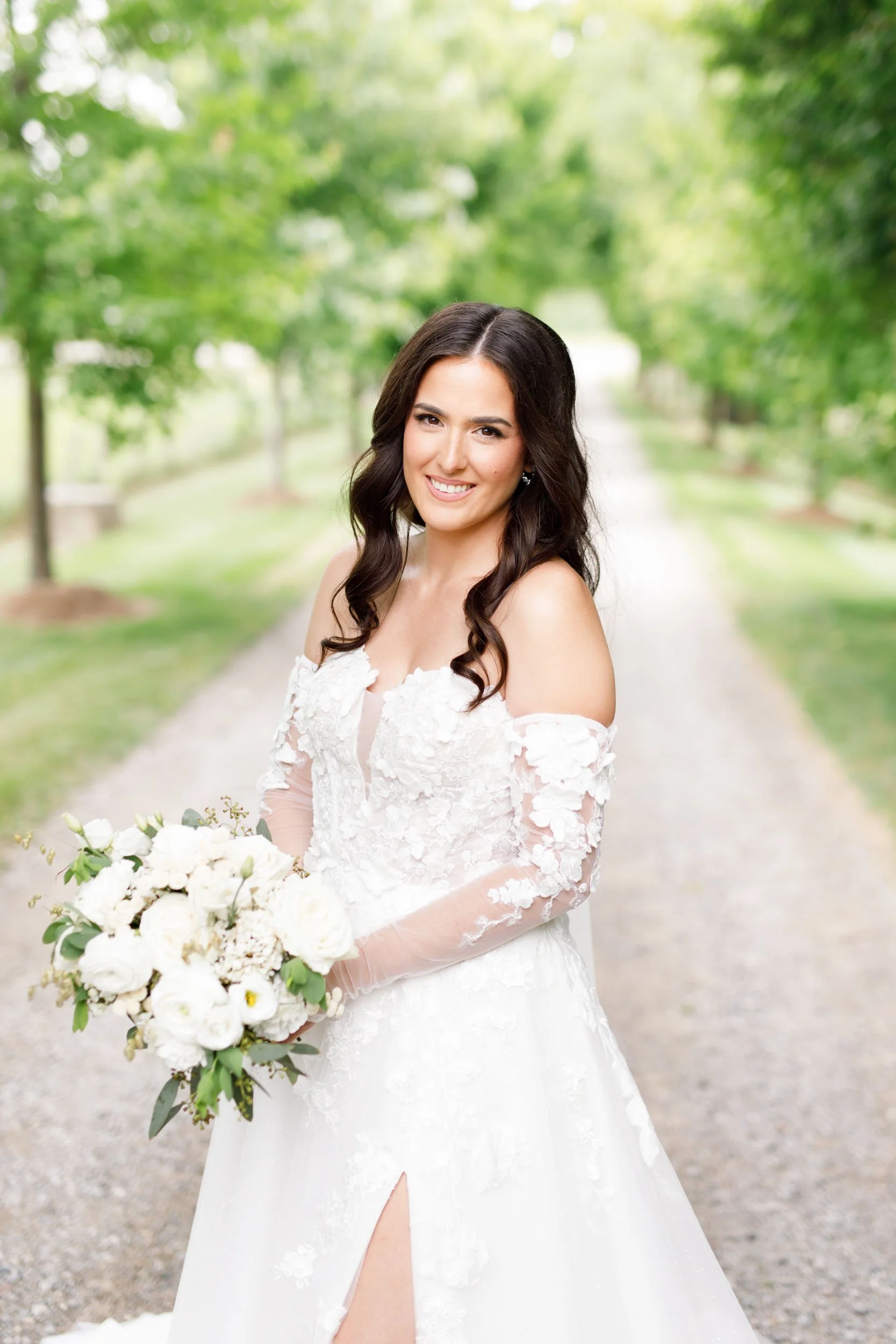 Bride smiling with her bouquet on the Cambium Farms driveway in Alton, Ontario
