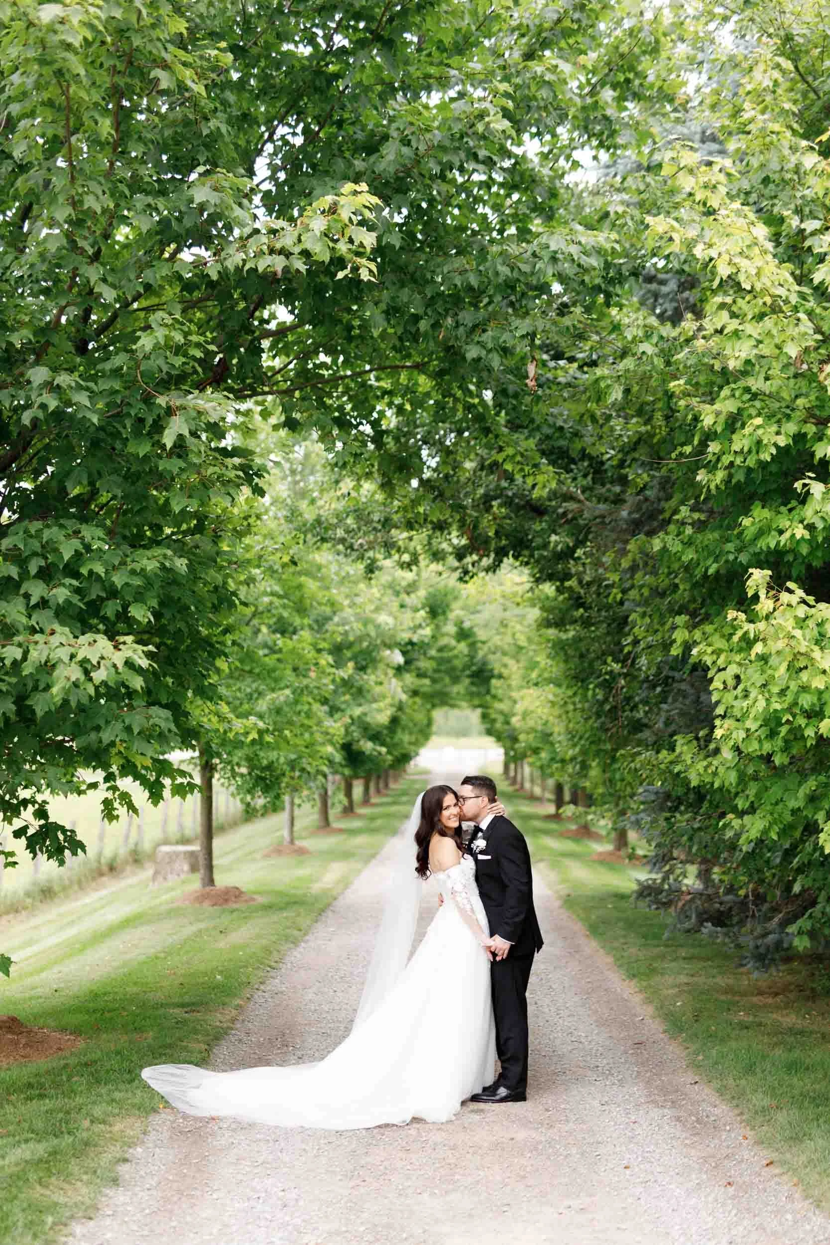 Bride and groom walking together under trees at a Cambium Farms wedding in Alton, Ontario