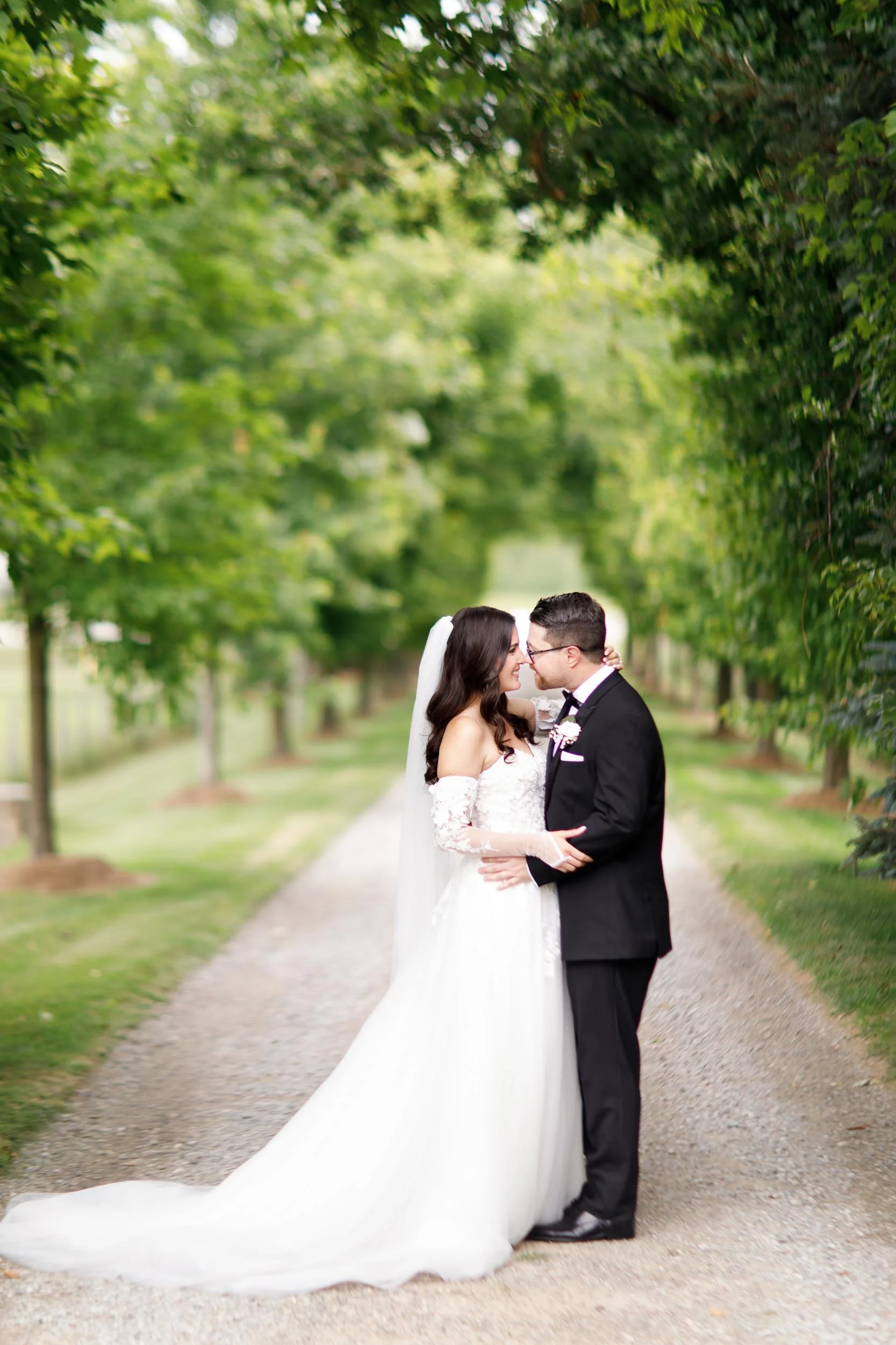 Bride and groom kissing during portraits on the Cambium Farms driveway in Alton, Ontario