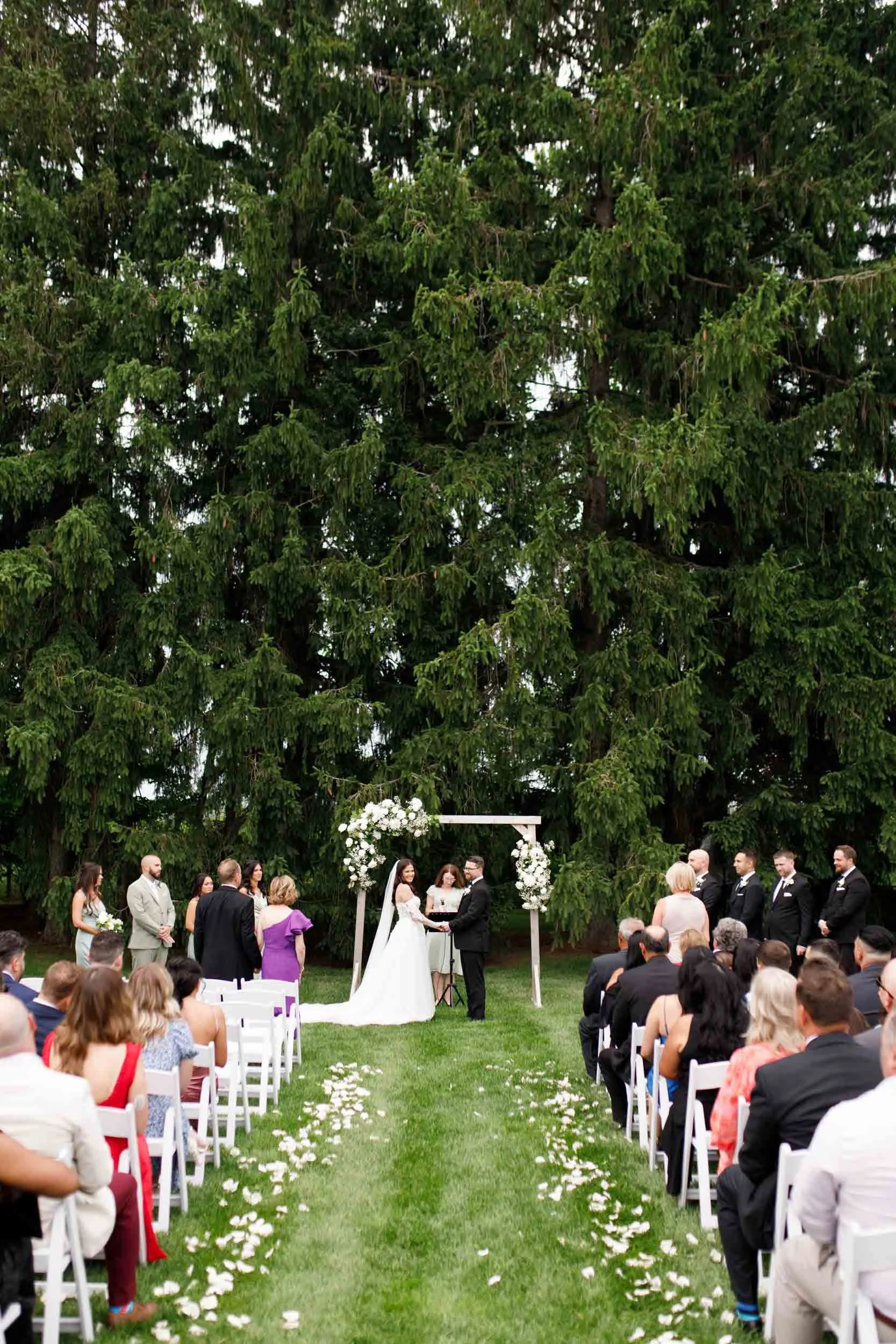 Outdoor wedding ceremony setup with guests and arbor at Cambium Farms in Alton, Ontario