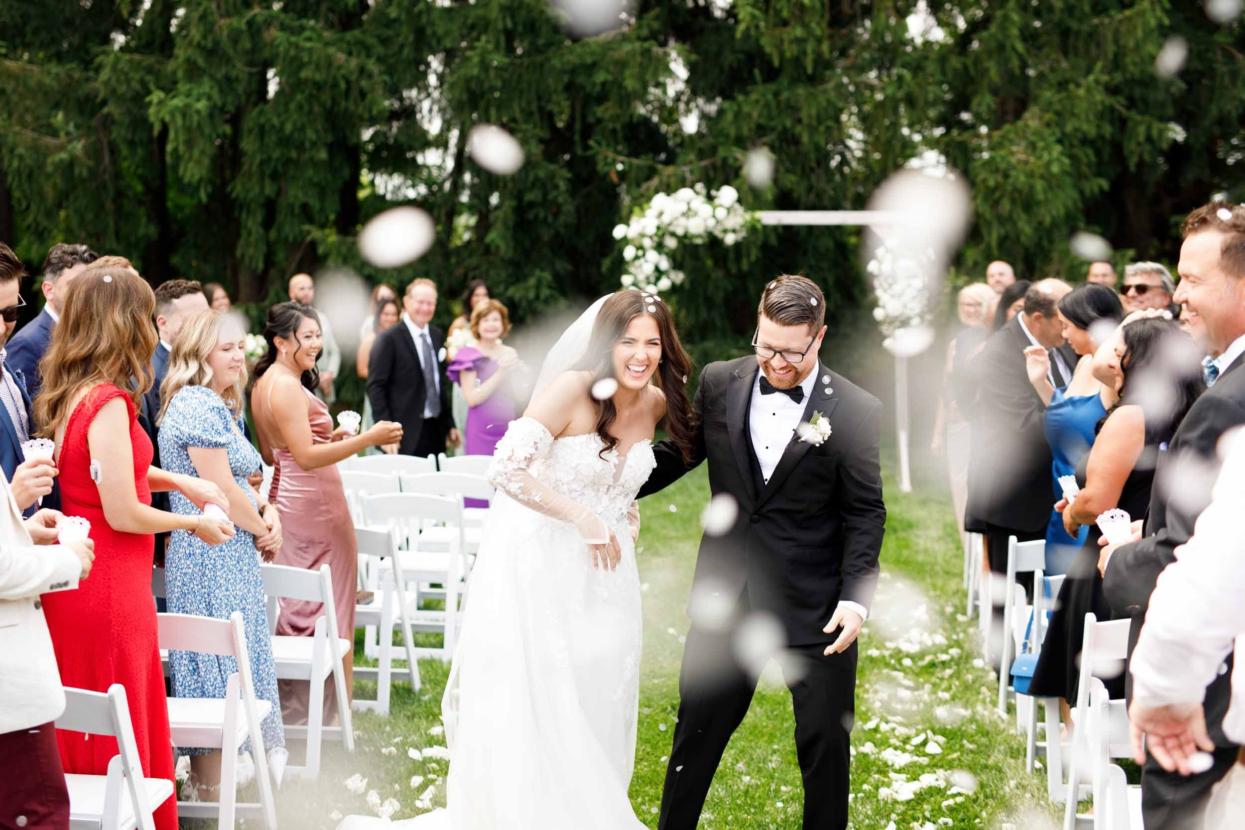 Bride and groom holding hands during their joyful confetti exit at Cambium Farms in Alton, Ontario