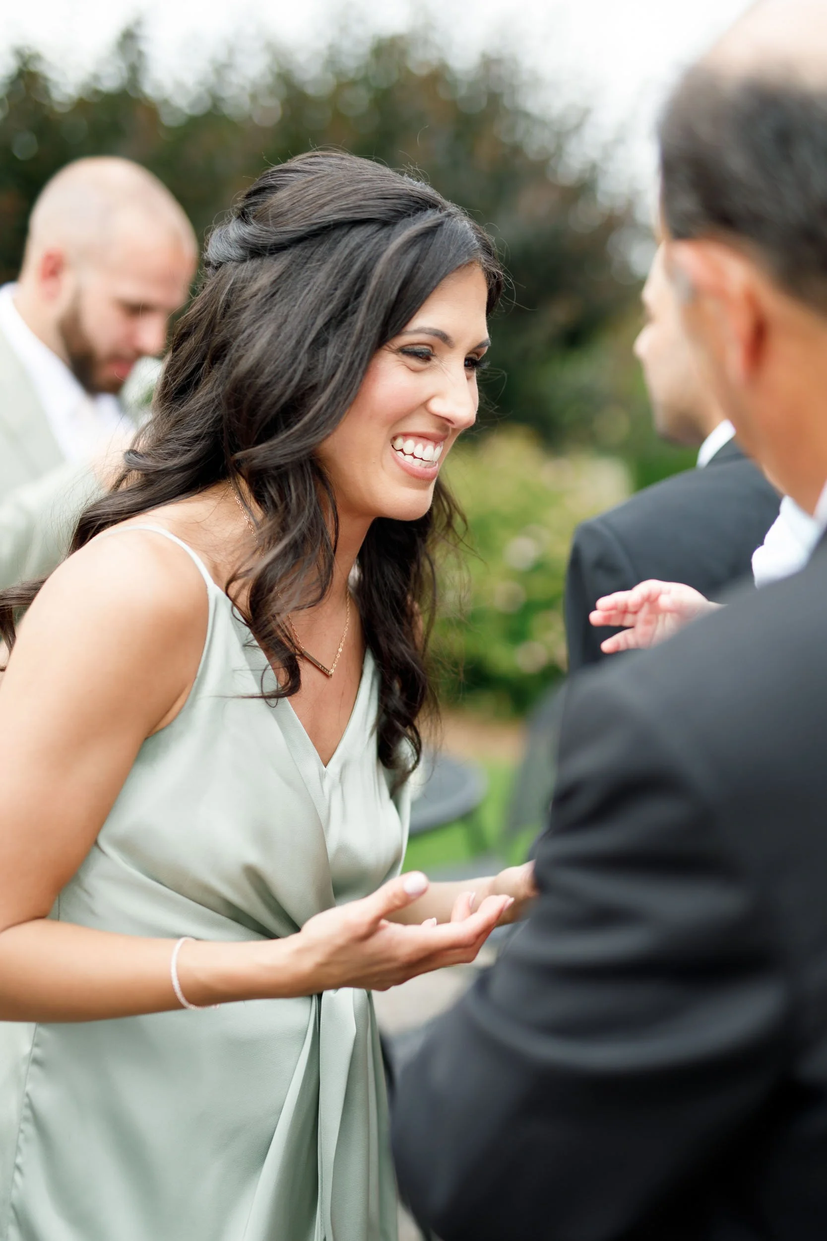 Bridesmaid laughing while talking with guests at a Cambium Farms wedding in Alton, Ontario