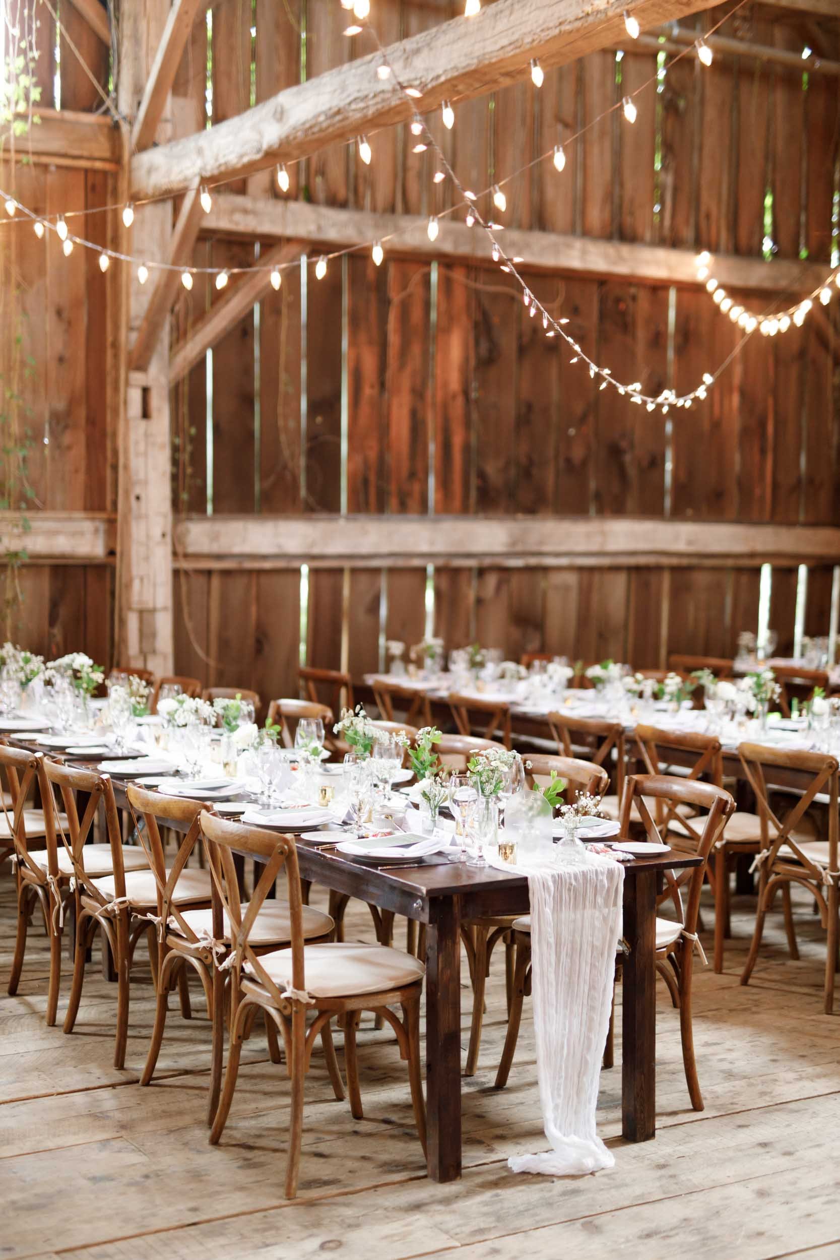 Long banquet tables with string lights inside the Cambium Farms wedding barn in Alton, Ontario