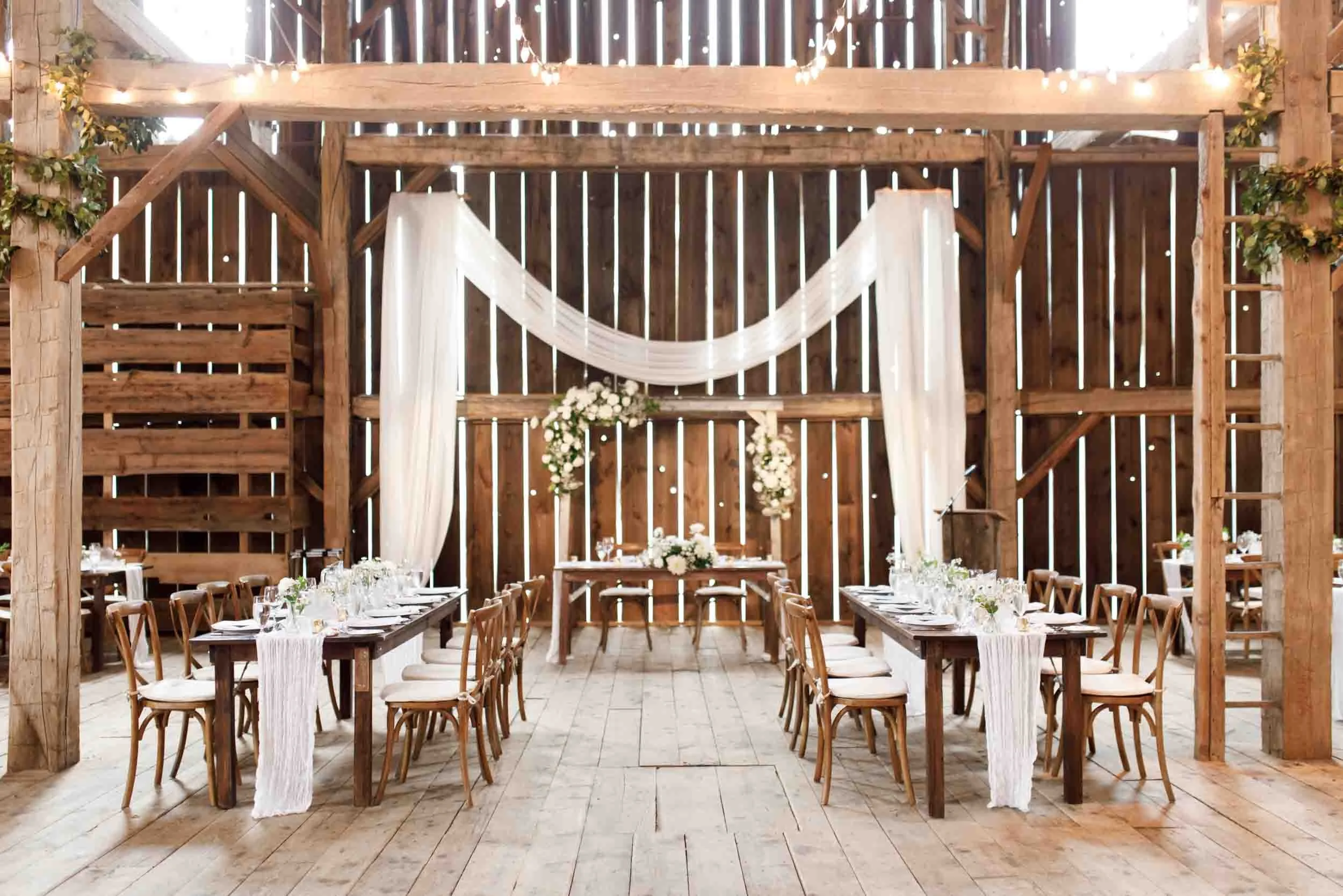 Sweetheart table and ceremony backdrop inside the Cambium Farms barn in Alton, Ontario