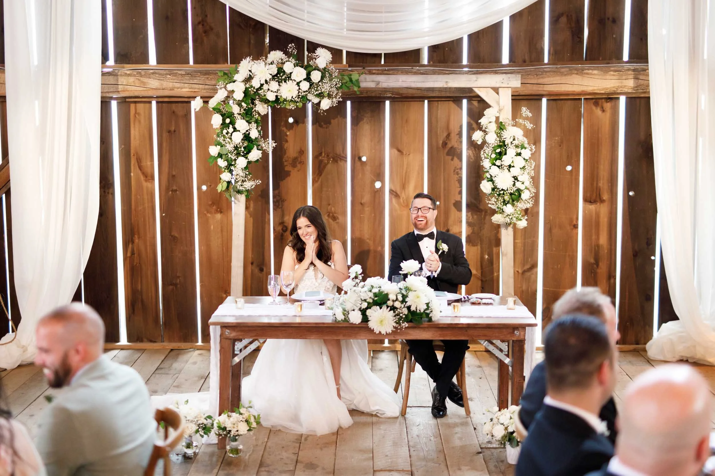 Bride and groom listening to wedding speeches at Cambium Farms in Alton, Ontario