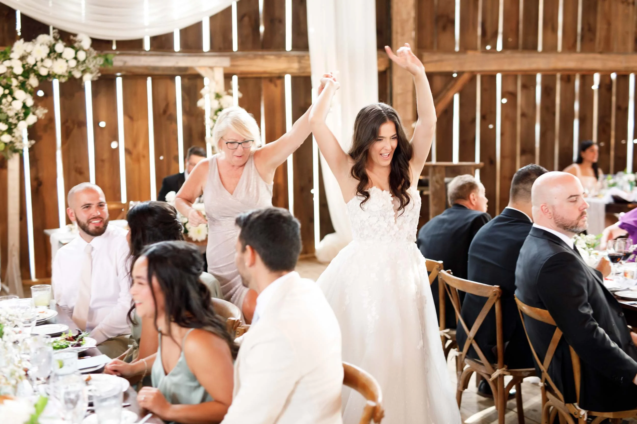 Bride raising her arms during a joyful wedding toast at Cambium Farms in Alton, Ontario