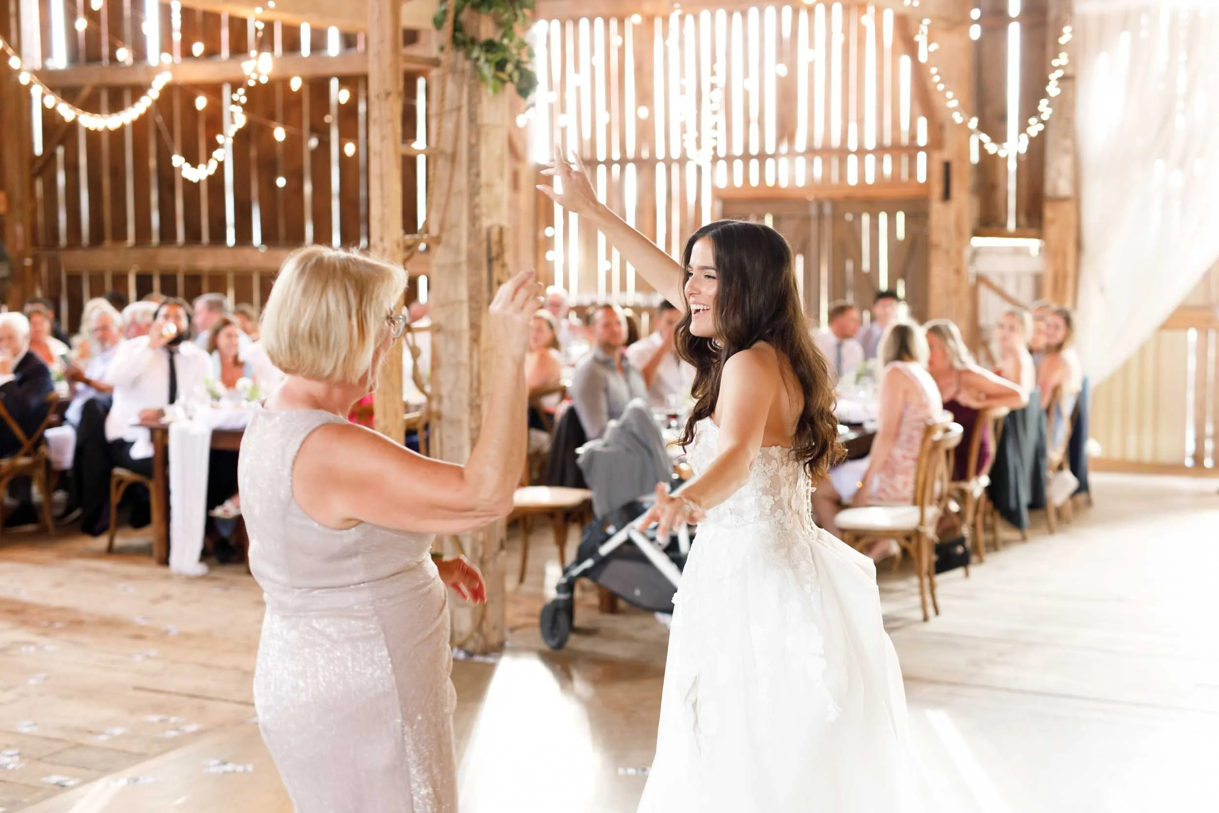 Bride and her mother dancing together inside the Cambium Farms barn in Alton, Ontario
