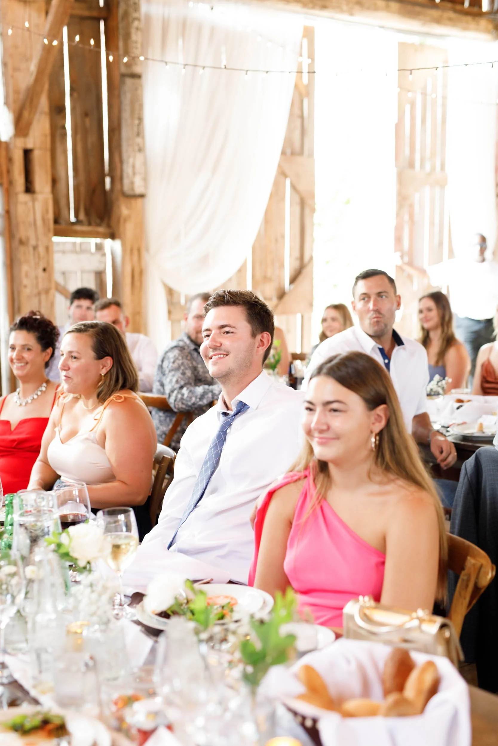 Wedding guests seated at reception tables inside the Cambium Farms barn in Alton, Ontario