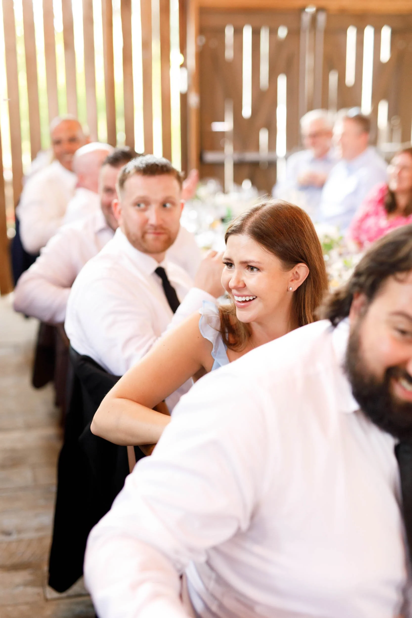 Guests smiling and watching the wedding speeches at Cambium Farms in Alton, Ontario