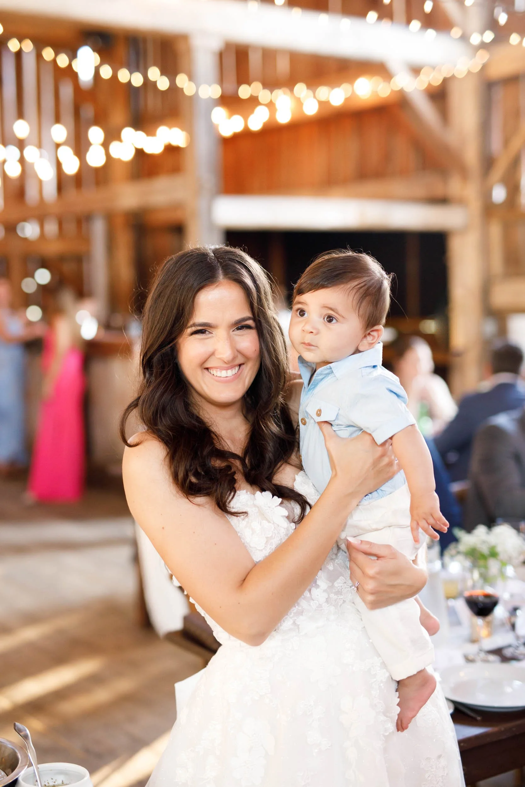 Bride holding a baby during the wedding reception at Cambium Farms in Alton, Ontario