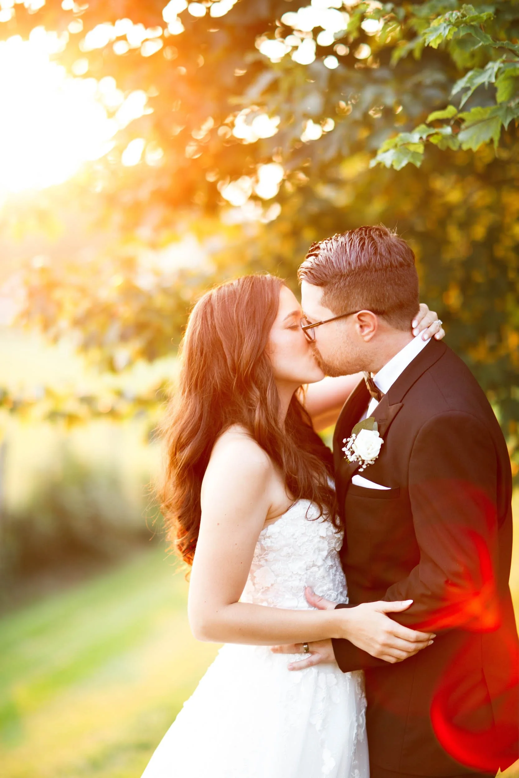Wide view of bride and groom walking through the trees at sunset at Cambium Farms in Alton, Ontario