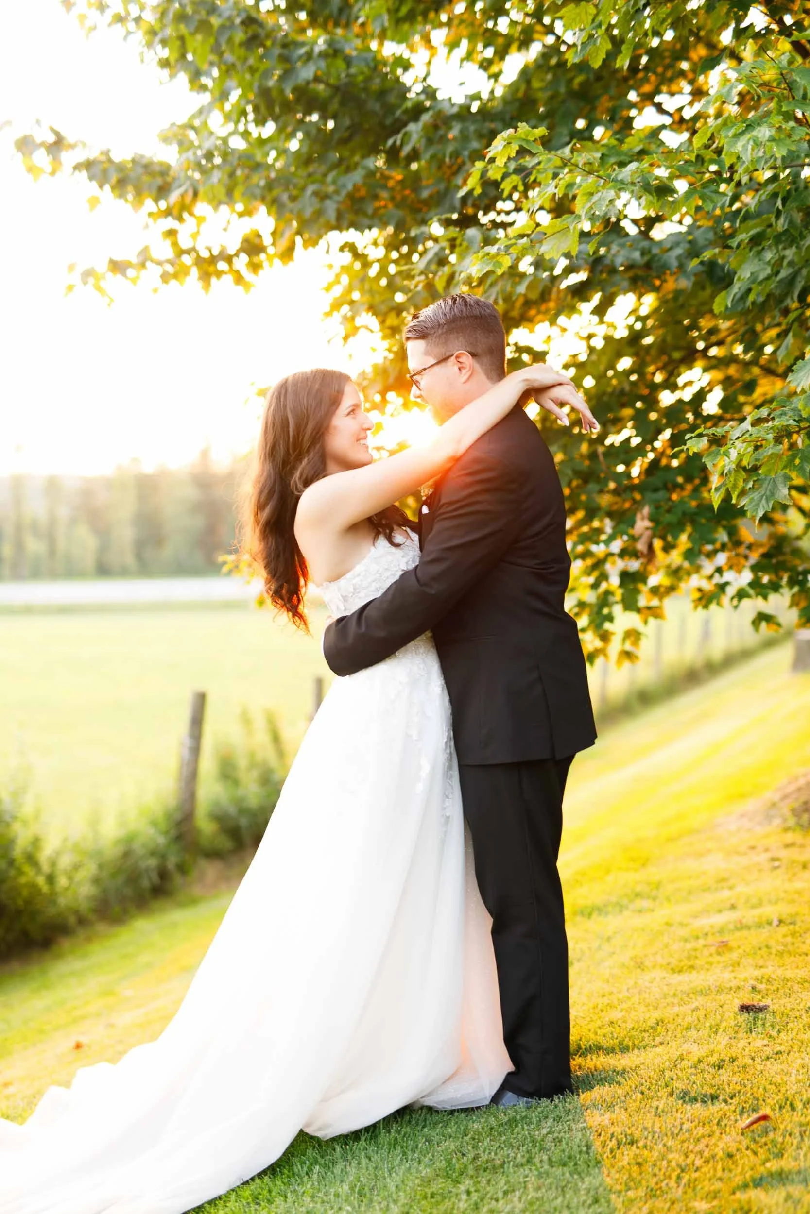 Bride and groom embracing beneath glowing sunset light at Cambium Farms in Alton, Ontario