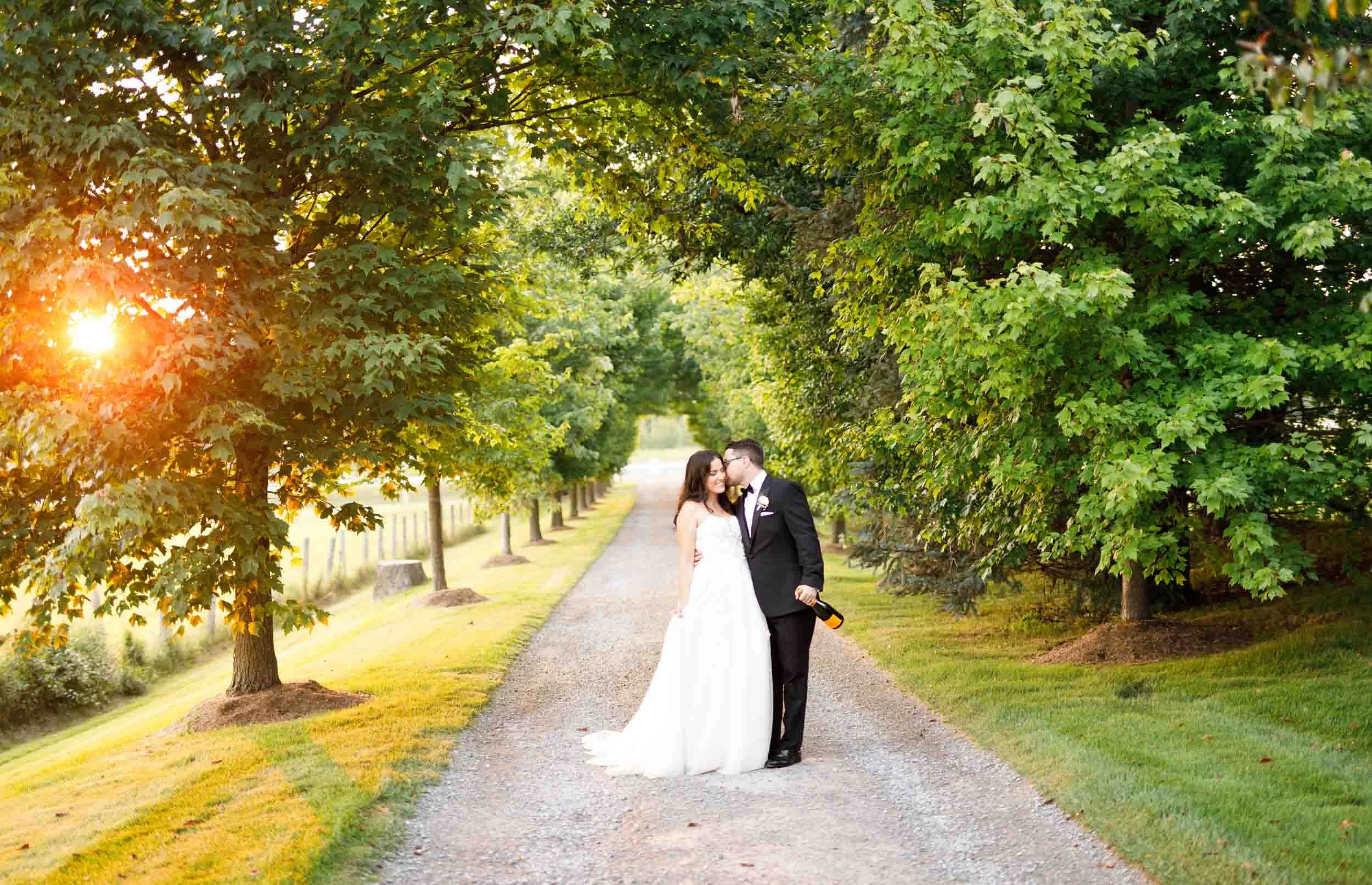 Bride and groom standing together on the Cambium Farms driveway at sunset in Alton, Ontario