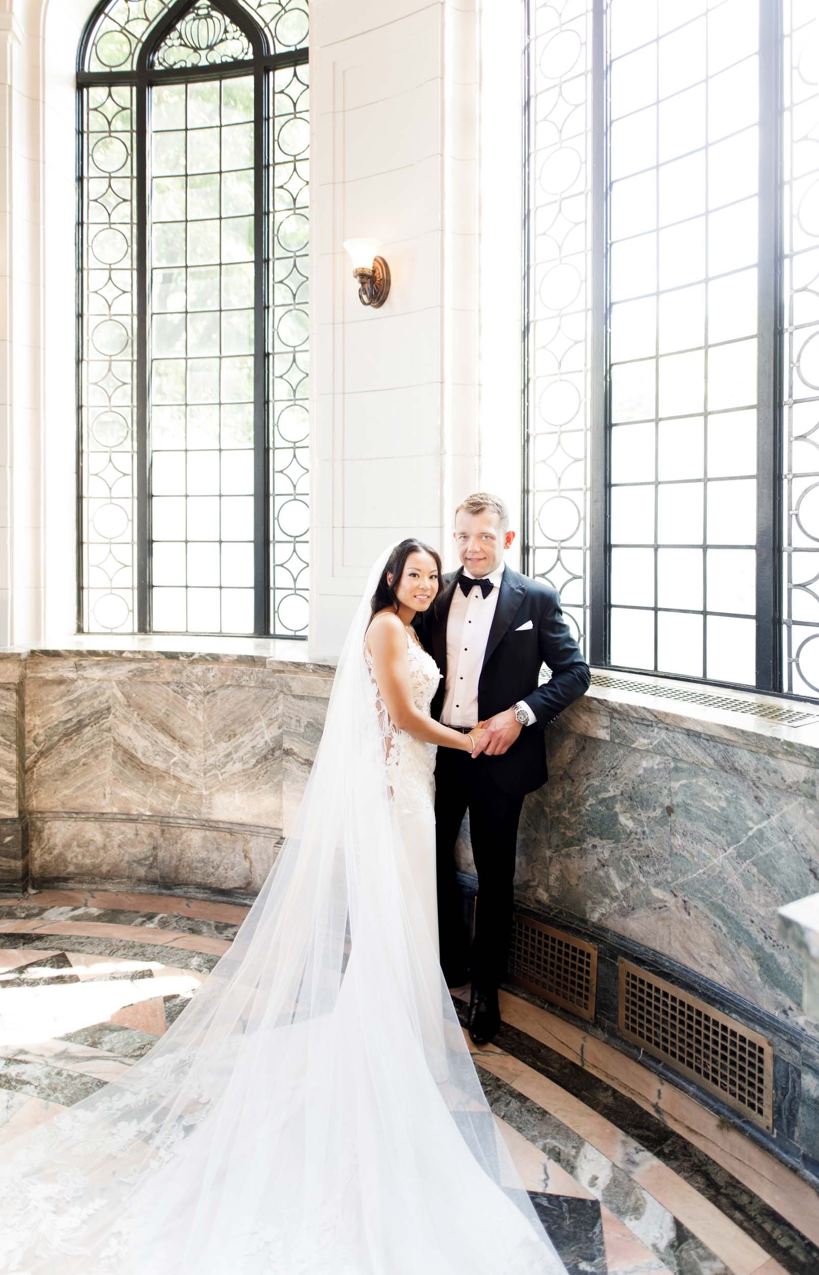Bride and groom by the tall windows at Casa Loma in Toronto