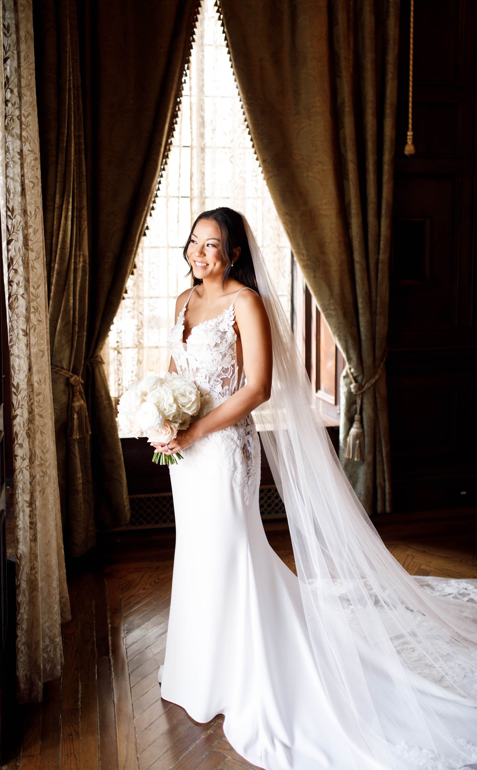 Bride holding bouquet in a sunlit window at Casa Loma in Toronto