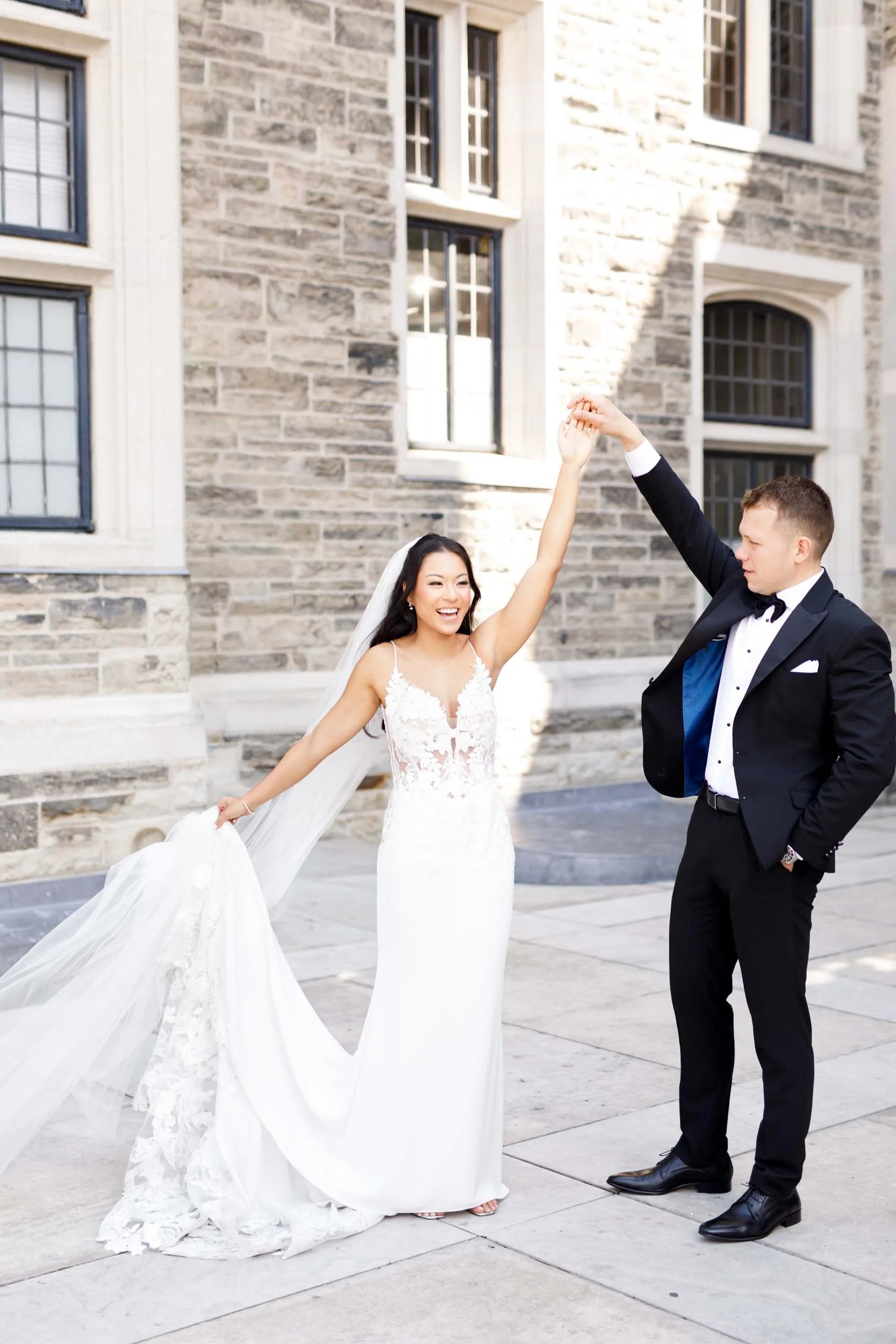 Bride twirling her wedding dress as the groom watches in the Casa Loma courtyard in Toronto