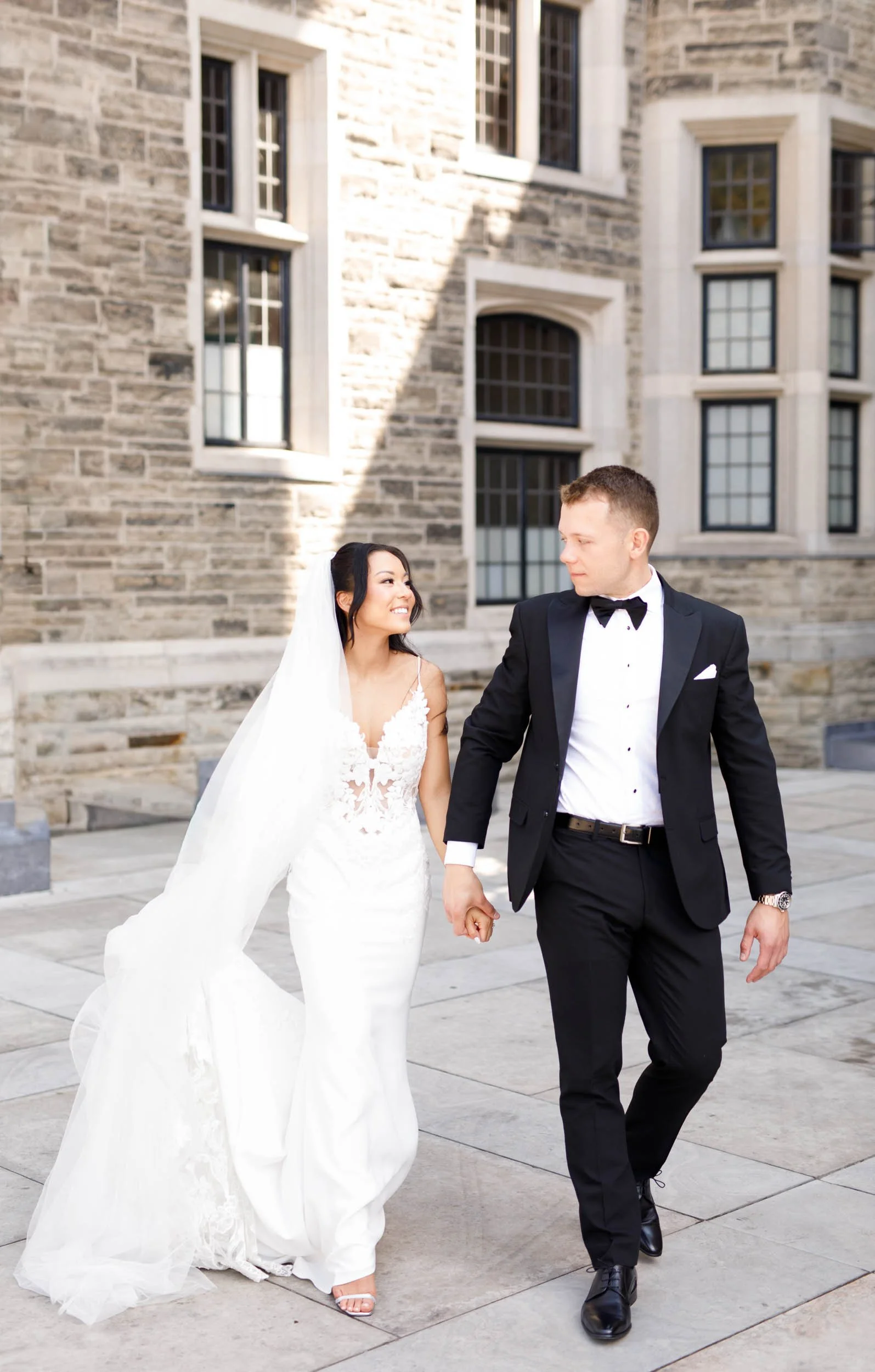 Bride and groom walking together through the Casa Loma courtyard in Toronto on their wedding day