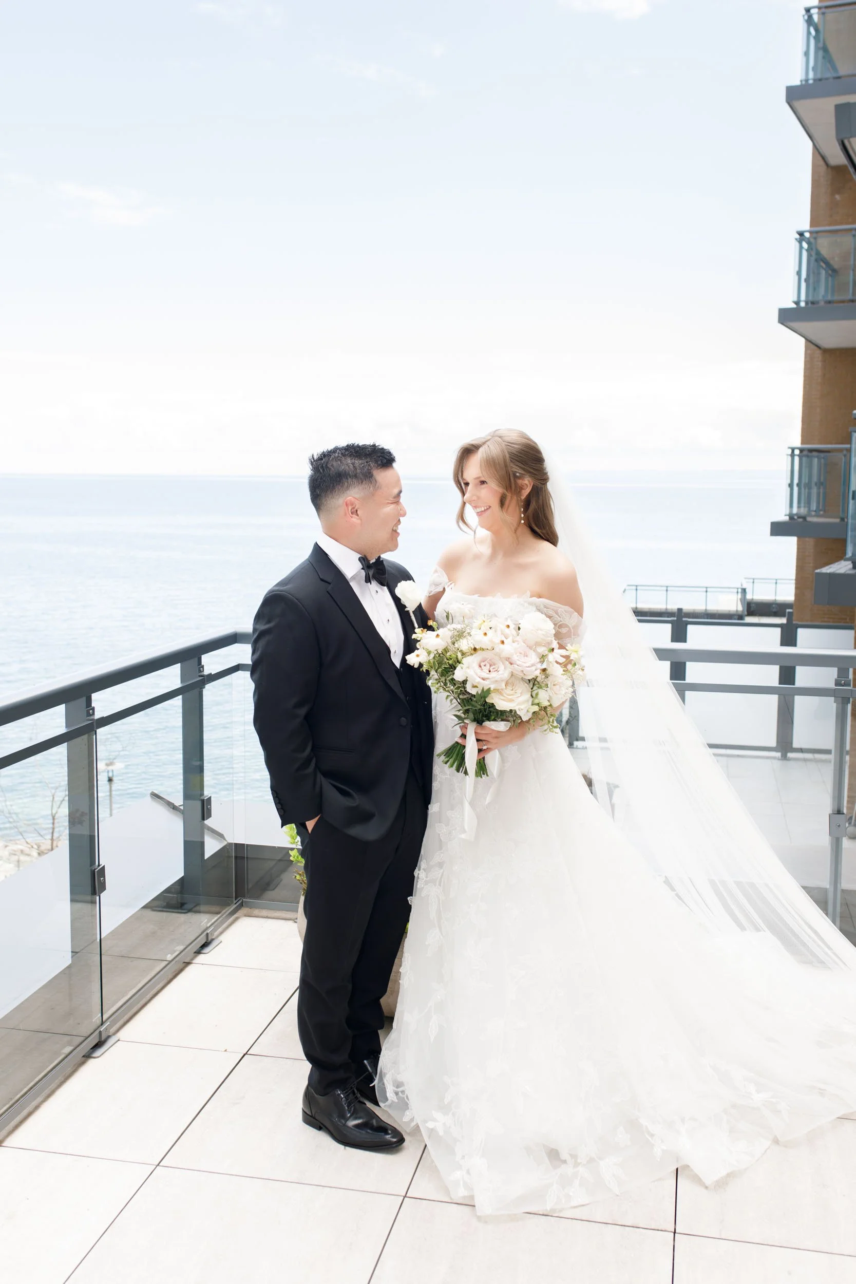 Bride and groom standing together on the waterfront terrace at the Pearle Hotel in Burlington Ontario