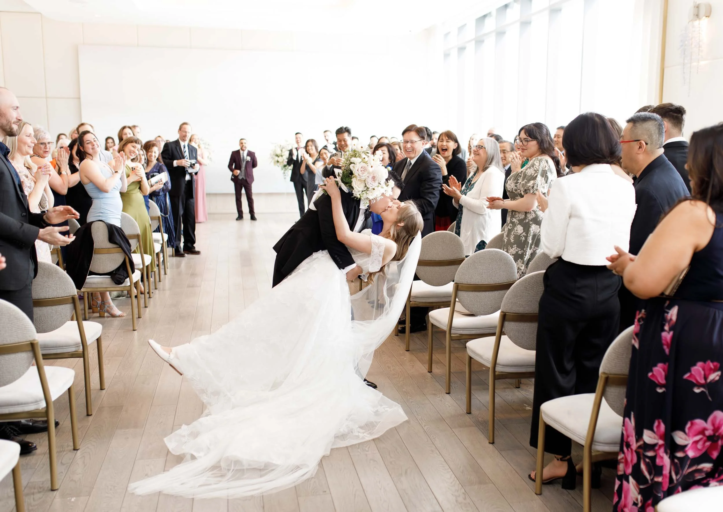 Wedding guests cheering as groom dips and kisses bride at Pearle Hotel wedding ceremony in Burlington Ontario