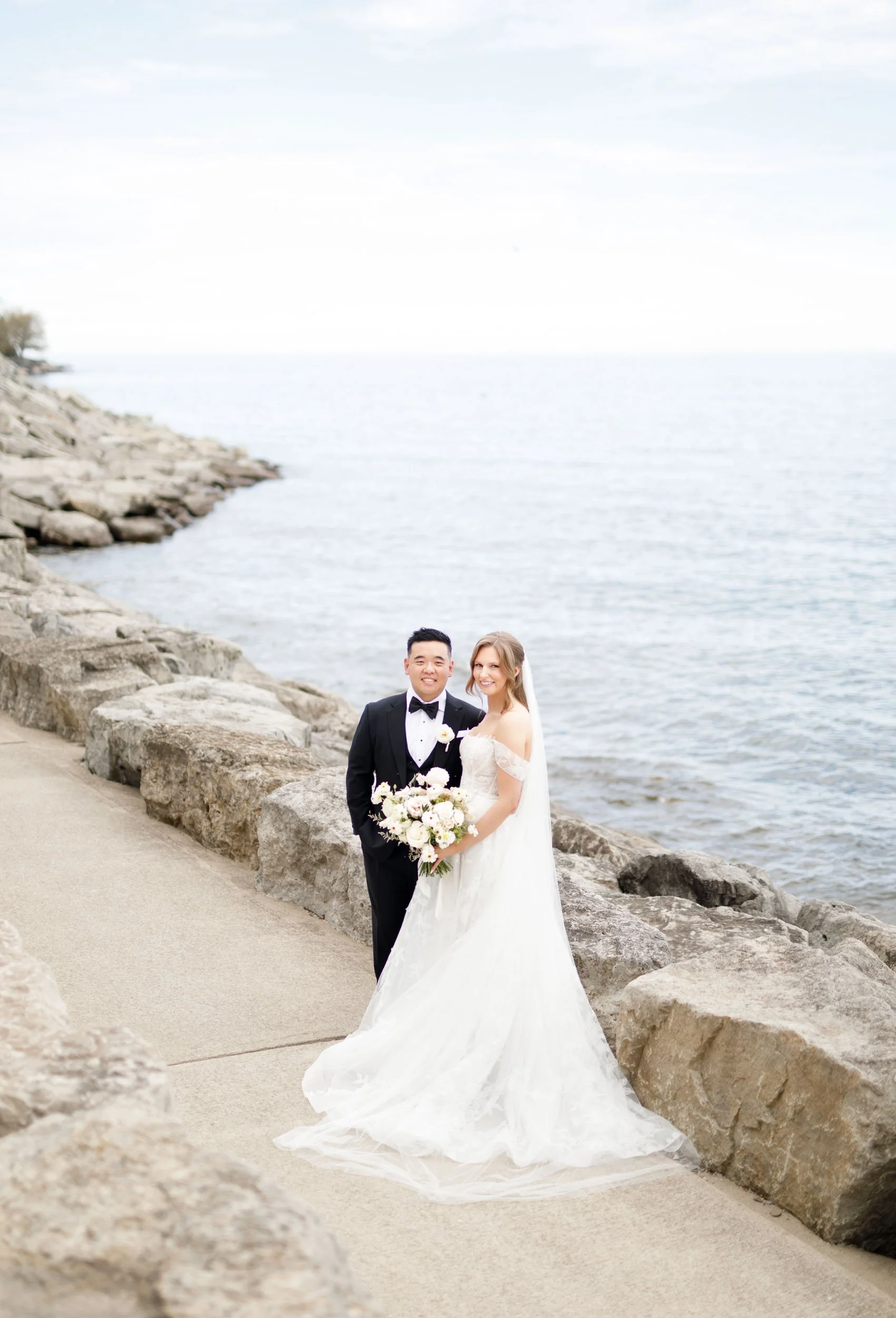 Bride and groom walking along the waterfront near the Pearle Hotel in Burlington Ontario