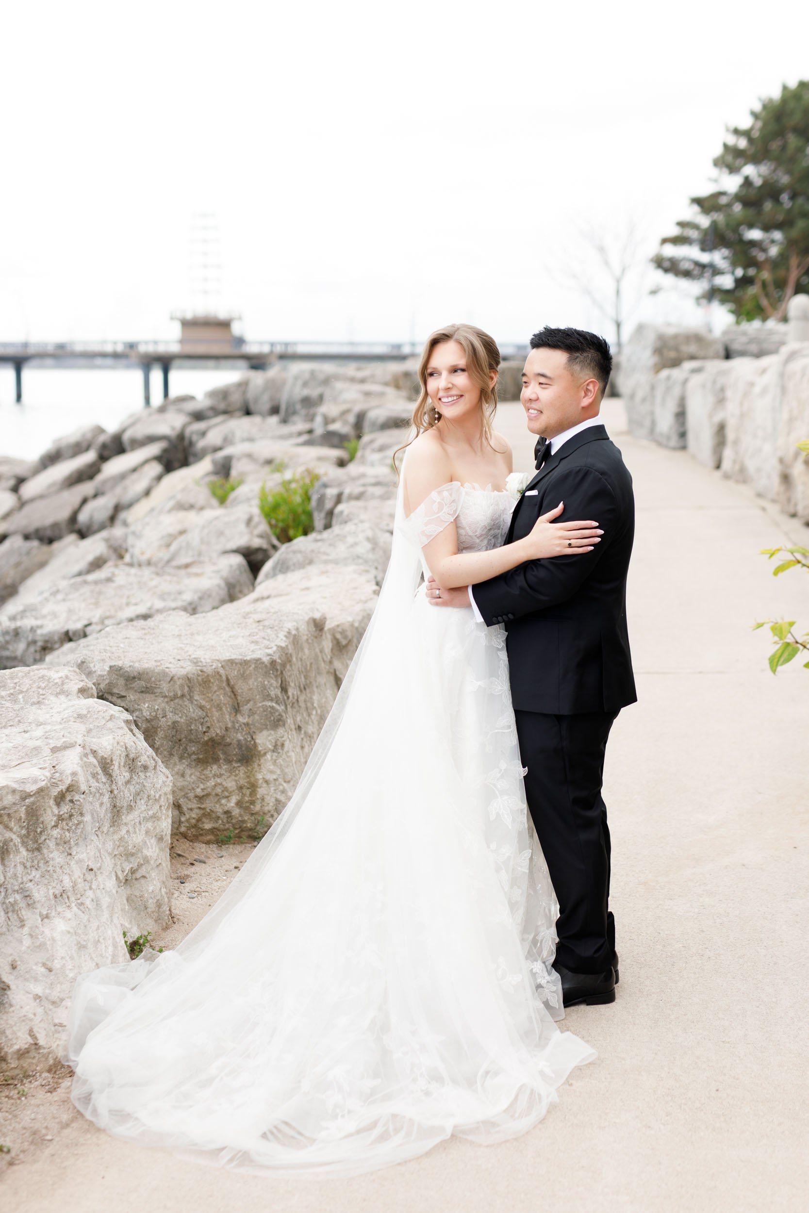 Bride and groom posing on the rocky shoreline at the Pearle Hotel in Burlington Ontario