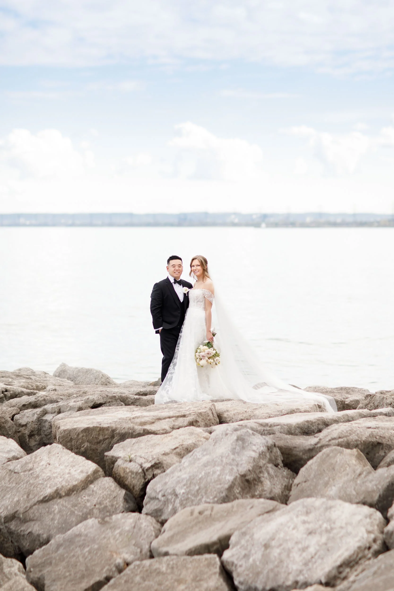 Bride and groom standing together by Lake Ontario at the Pearle Hotel in Burlington Ontario