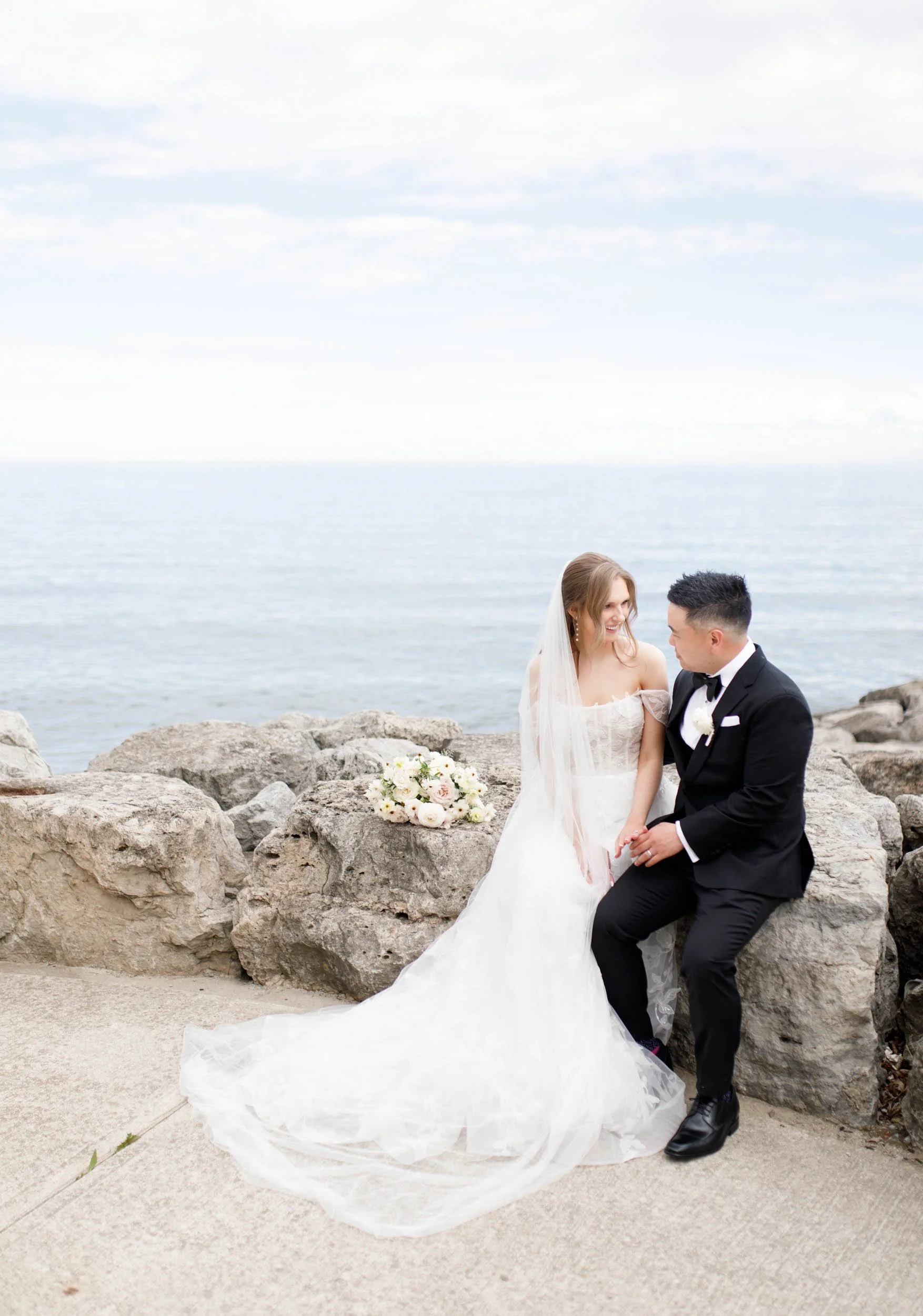 Bride and groom sitting together by Lake Ontario near the Pearle Hotel in Burlington Ontario