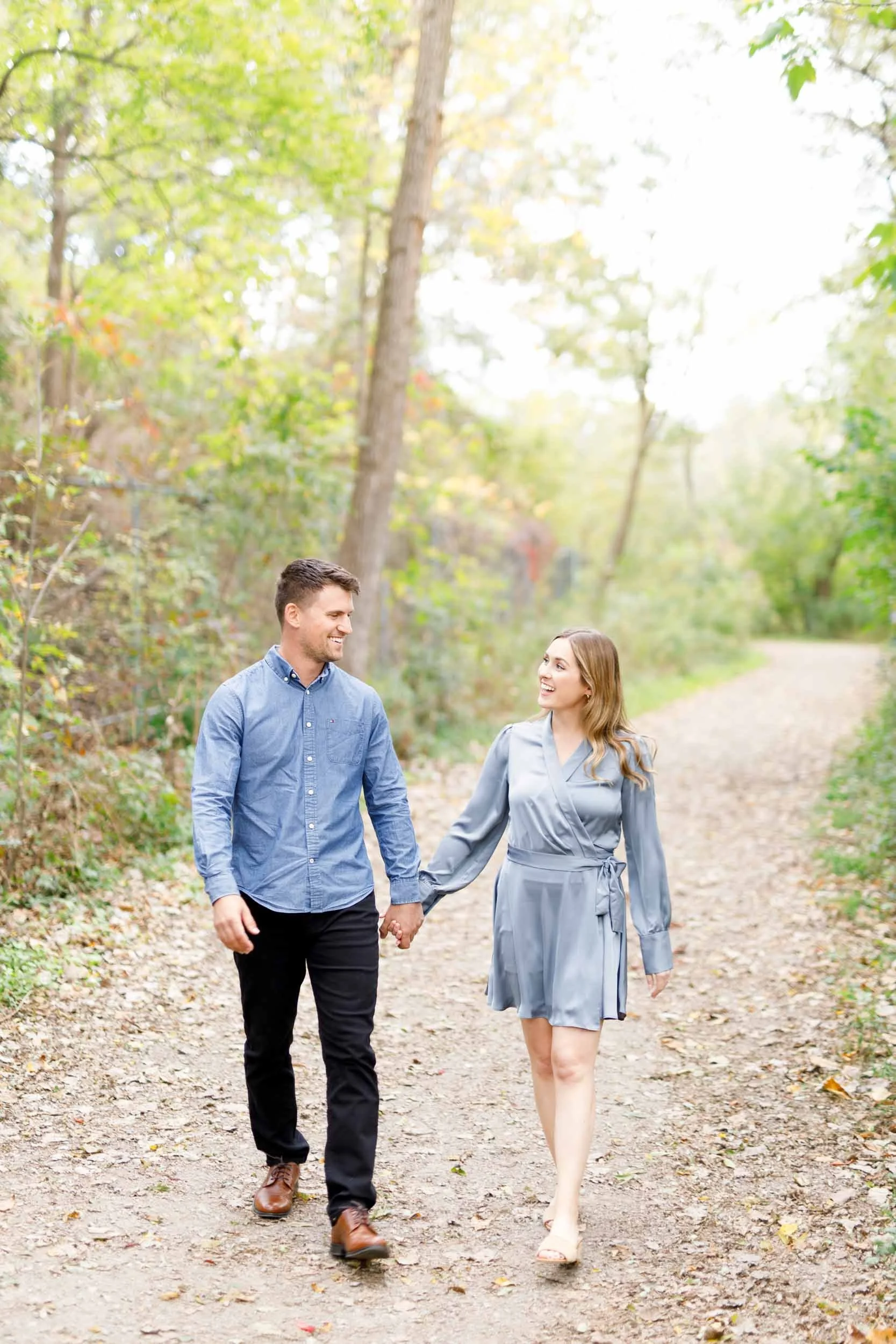 Engaged couple holding hands while walking at Grindstone Marsh Trail in Burlington Ontario during a fall engagement session