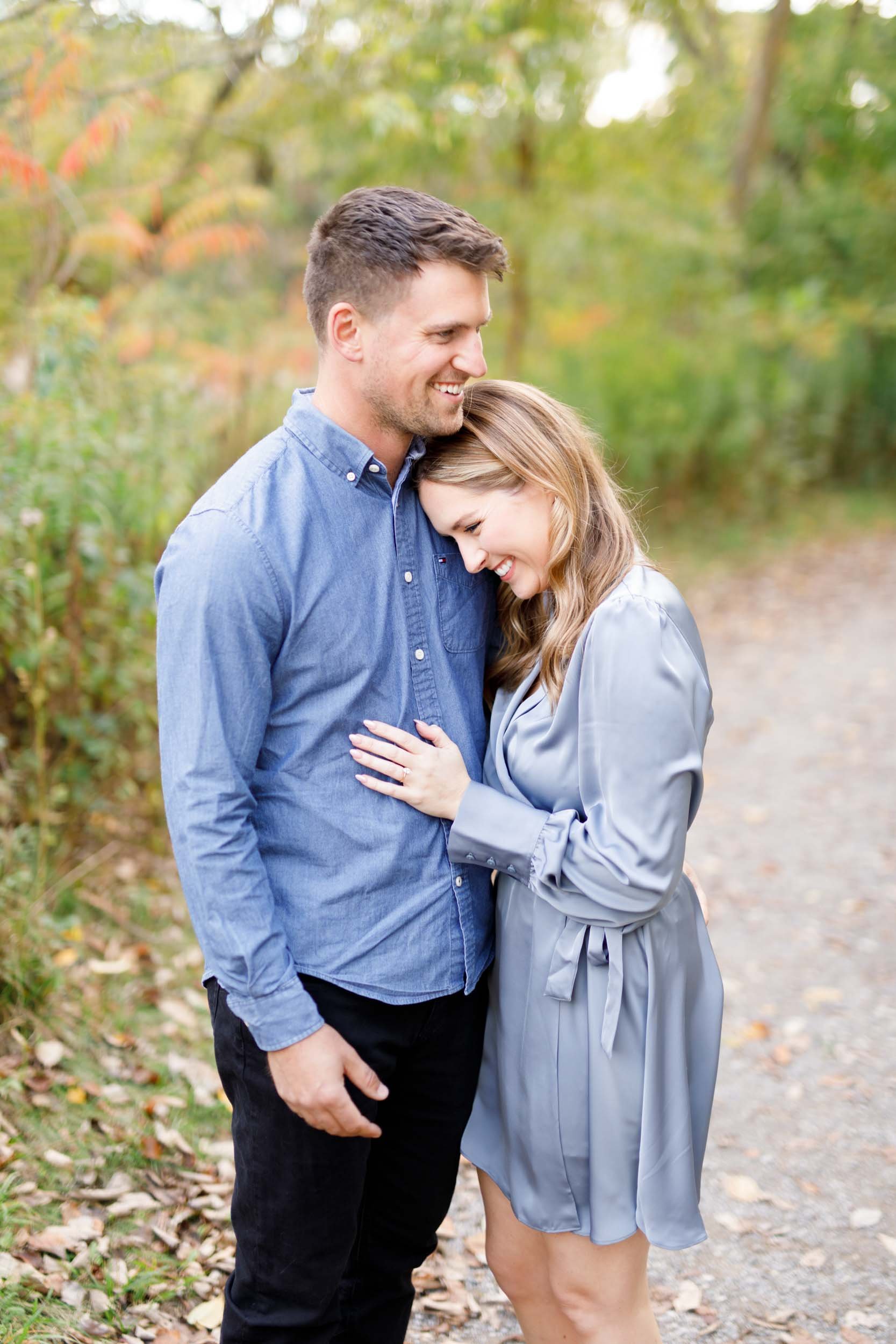 Engaged couple smiling together during a fall engagement shoot at Grindstone Marsh Trail in Burlington Ontario