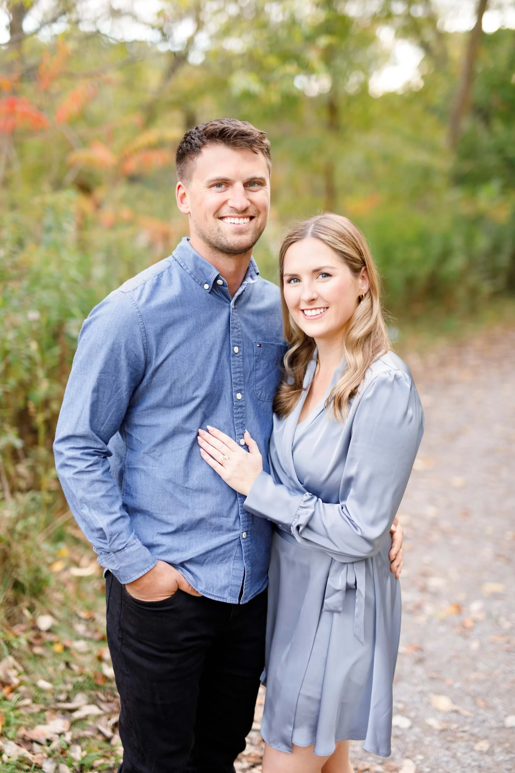 Happy engaged couple posing together on a wooded trail at Grindstone Marsh Trail in Burlington Ontario