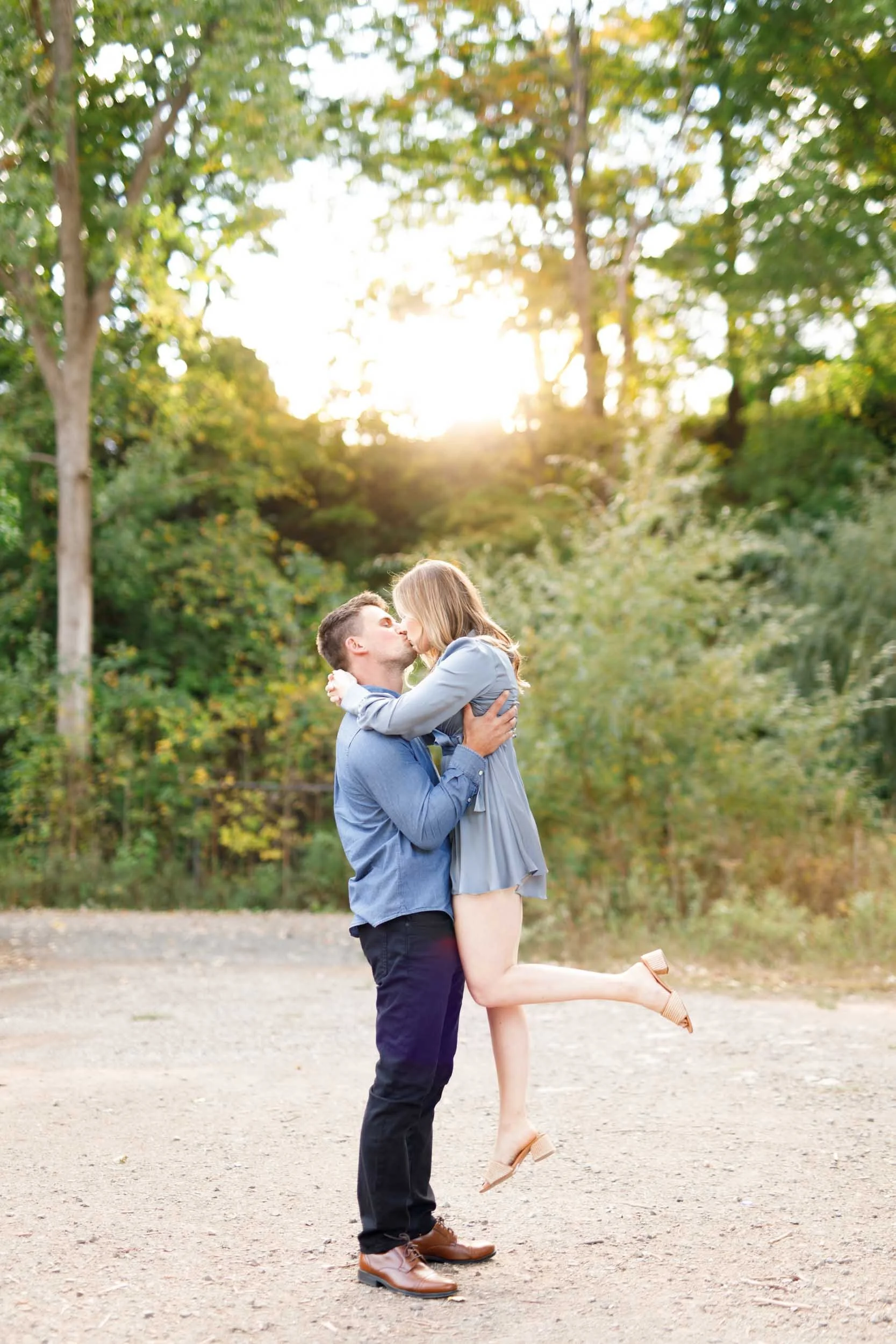 Engaged couple sharing a kiss on a forest trail at Grindstone Marsh Trail in Burlington Ontario