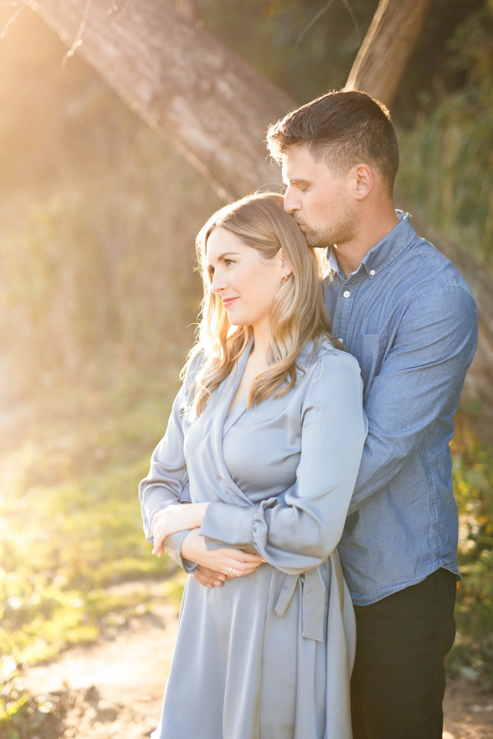 Engaged couple standing together in warm sunlight at Grindstone Marsh Trail in Burlington Ontario
