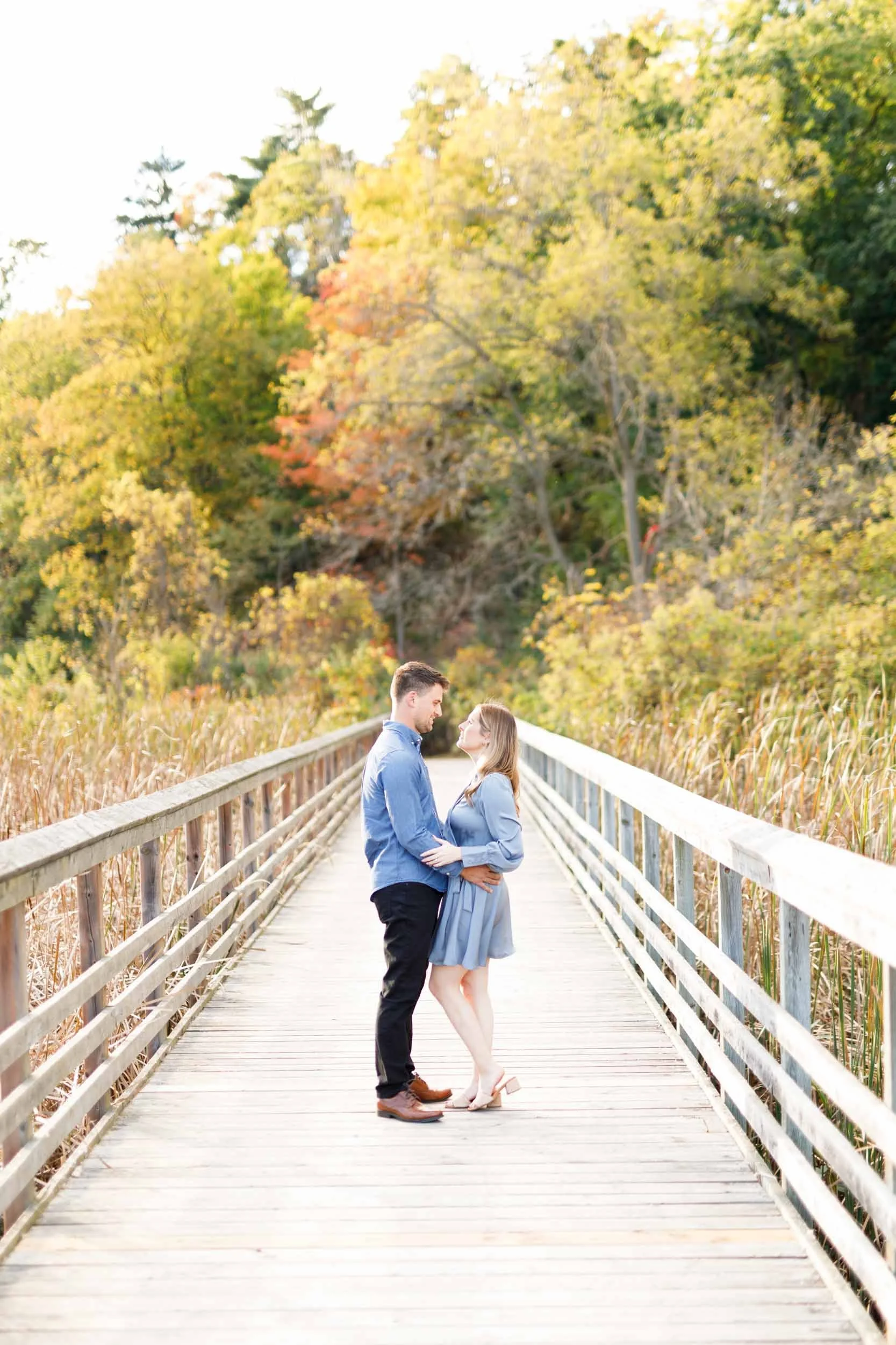 Romantic engagement photo of a couple kissing on a boardwalk at Grindstone Marsh Trail in Burlington Ontario