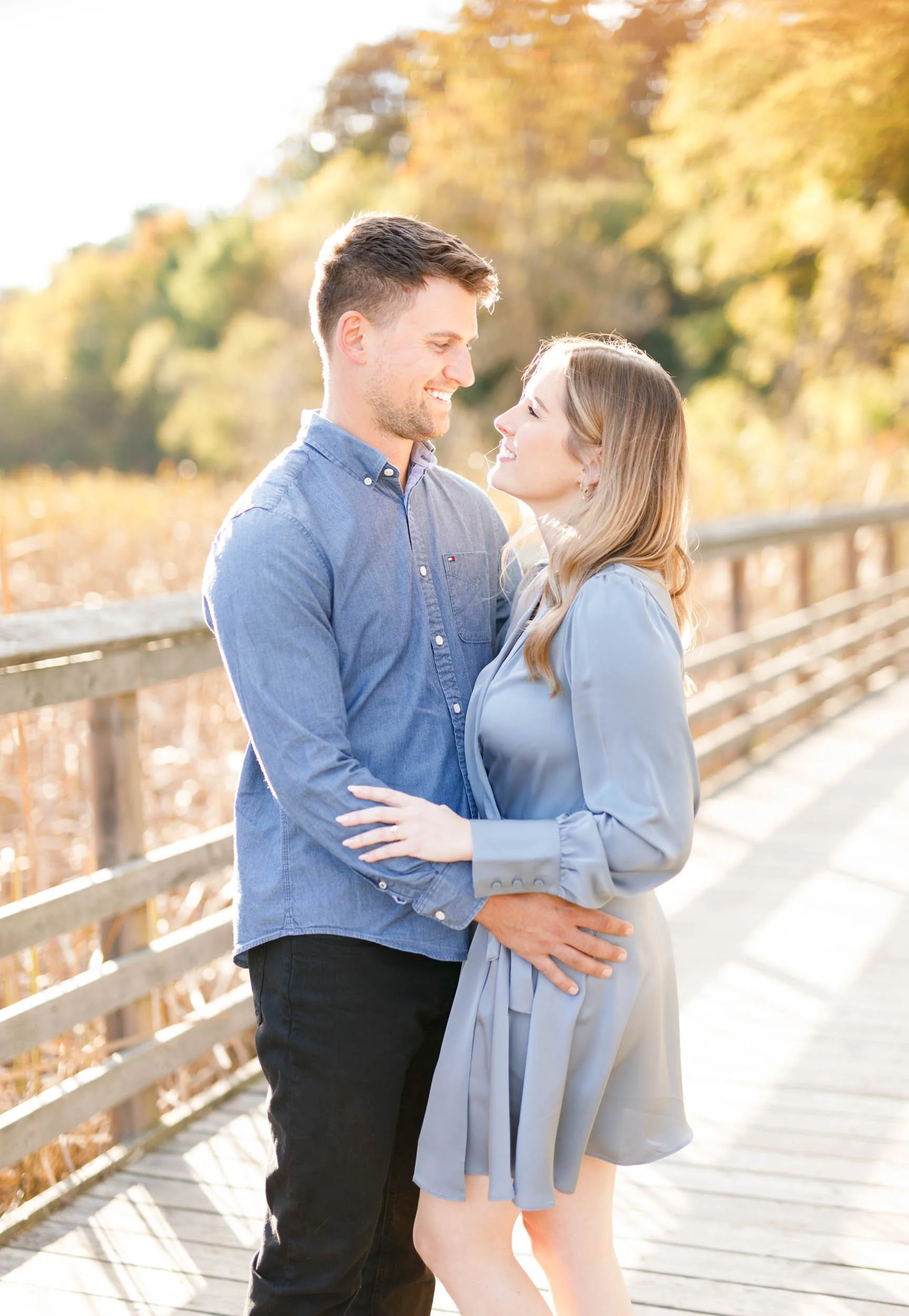 Engagement portrait of a couple holding each other on the boardwalk at Grindstone Marsh Trail in Burlington Ontario