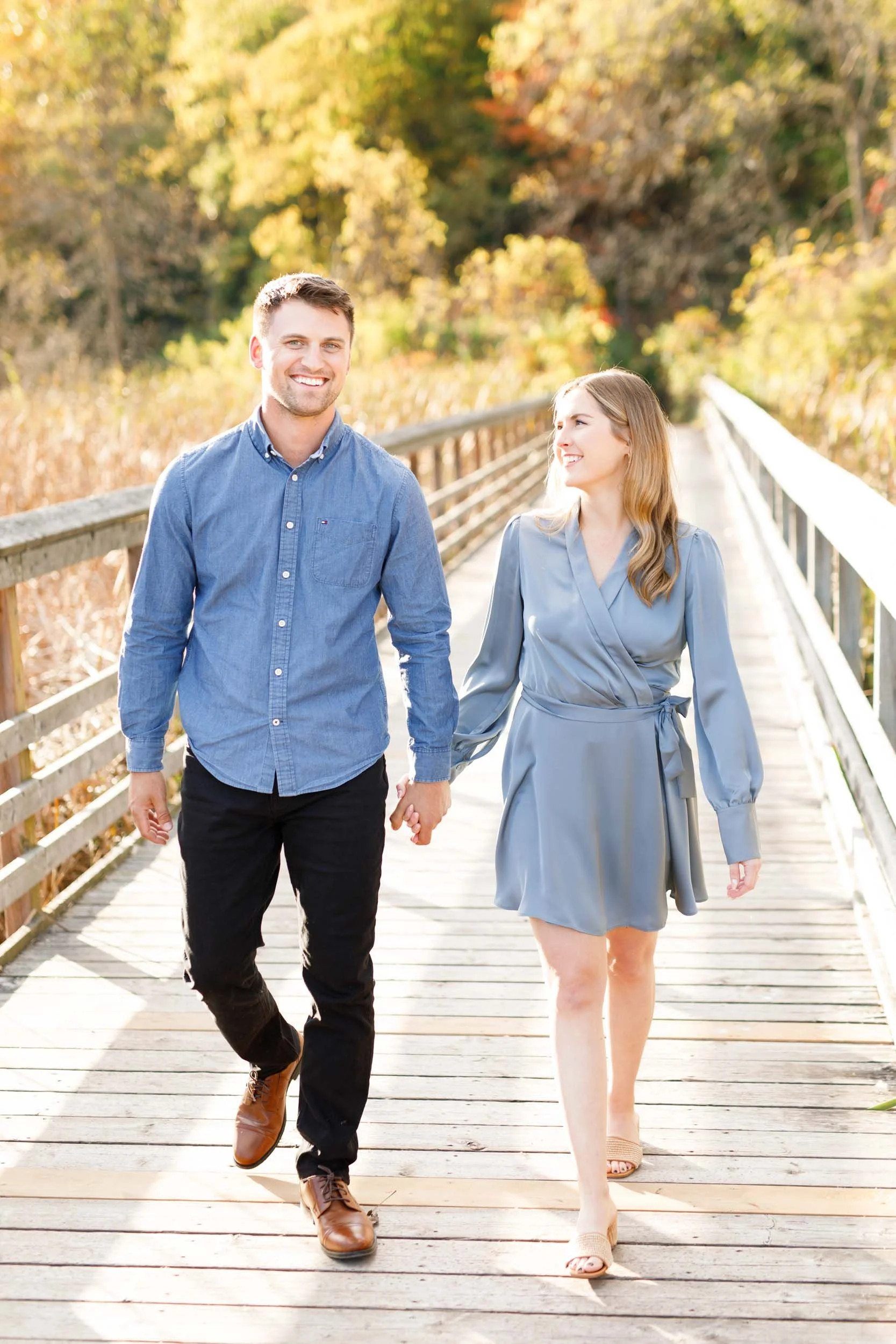 Couple walking hand in hand during a fall engagement session at Grindstone Marsh Trail in Burlington Ontario
