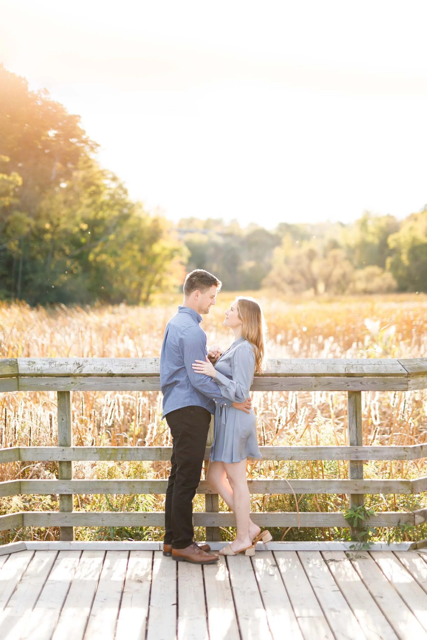 Engaged couple sharing a quiet moment on the boardwalk at Grindstone Marsh Trail in Burlington Ontario during a fall engagement session