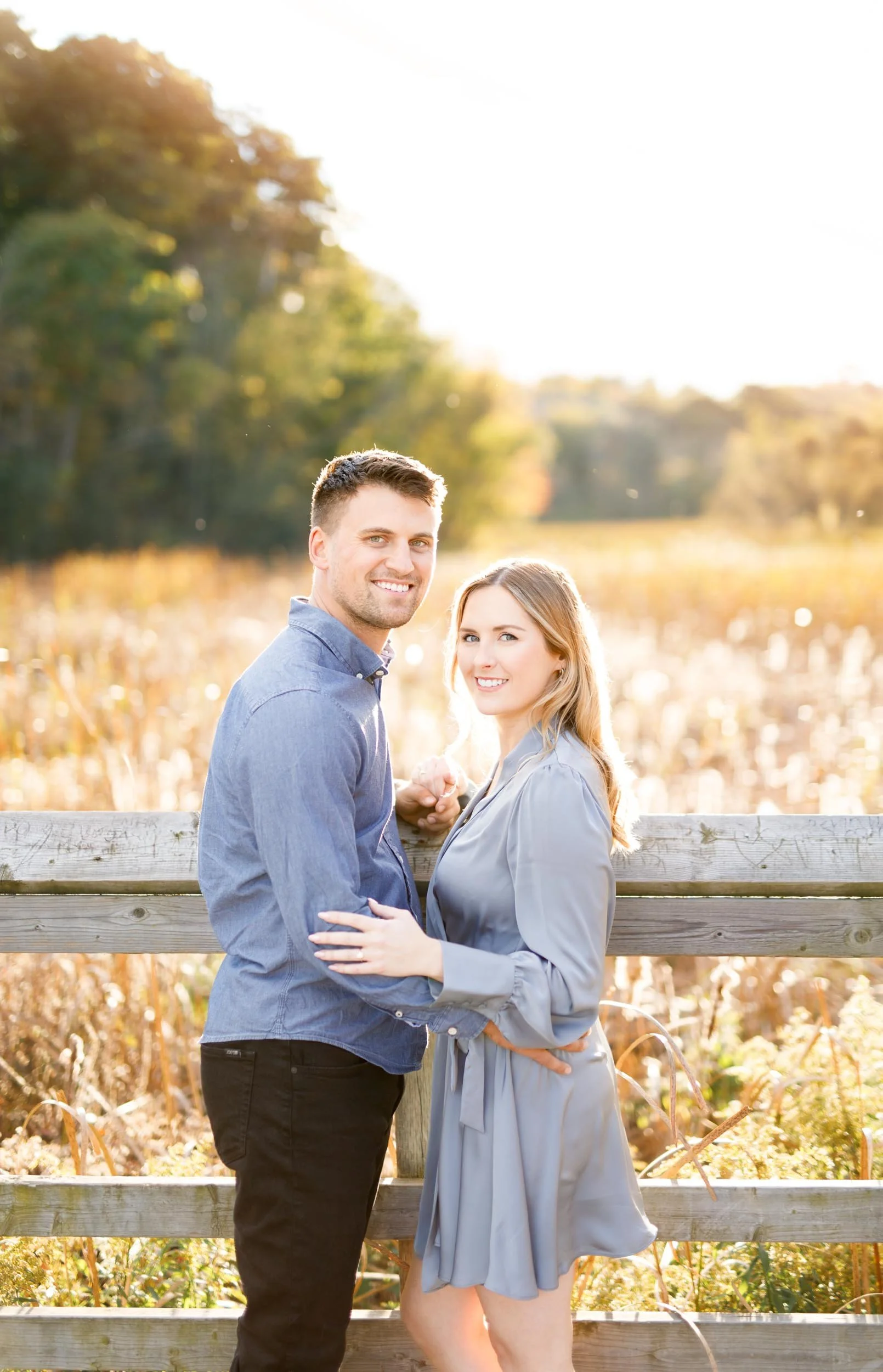 Engaged couple smiling at the camera during a fall engagement session at Grindstone Marsh Trail in Burlington Ontario