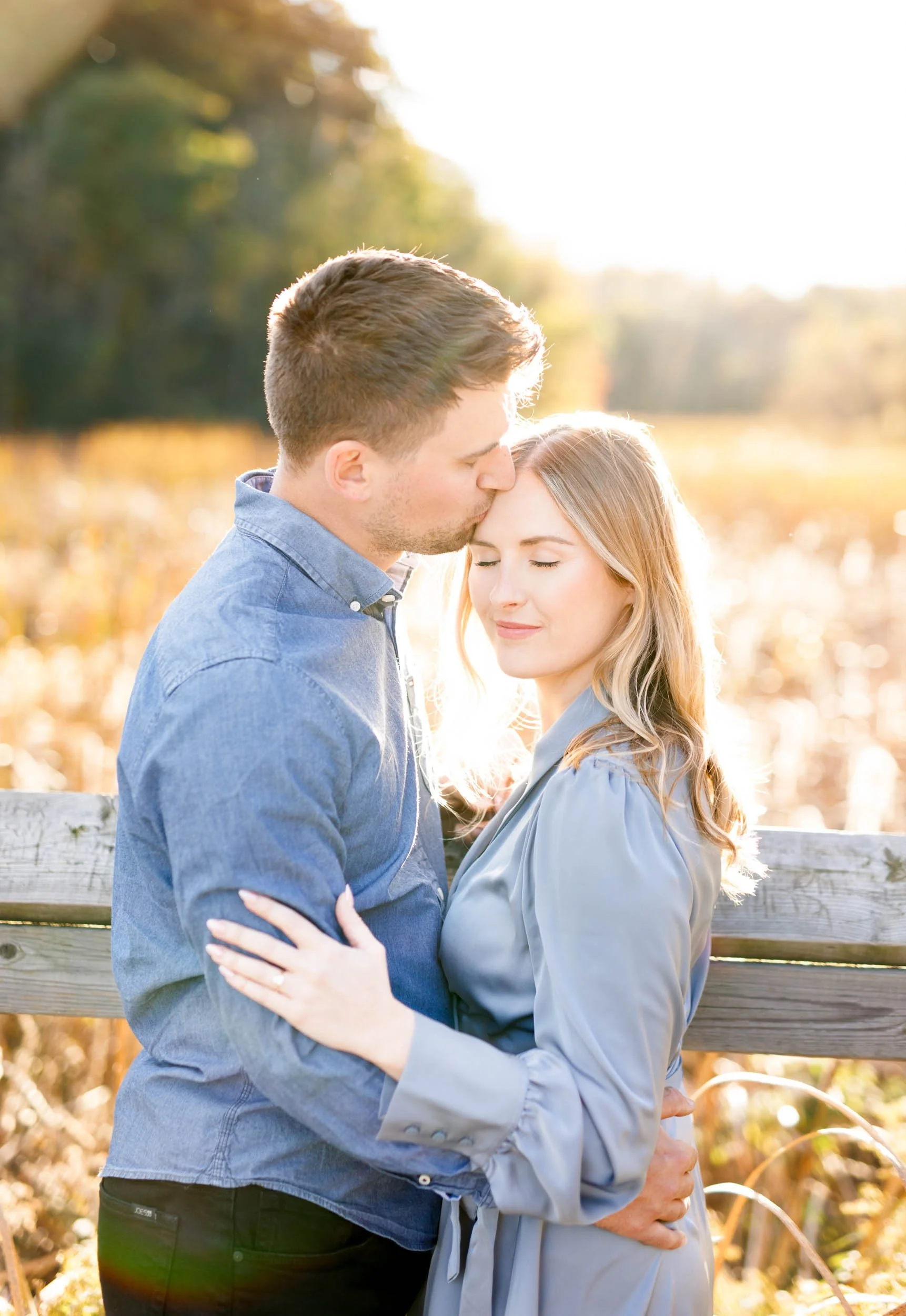 Close up engagement photo of a couple embracing at Grindstone Marsh Trail in Burlington Ontario with golden fall light