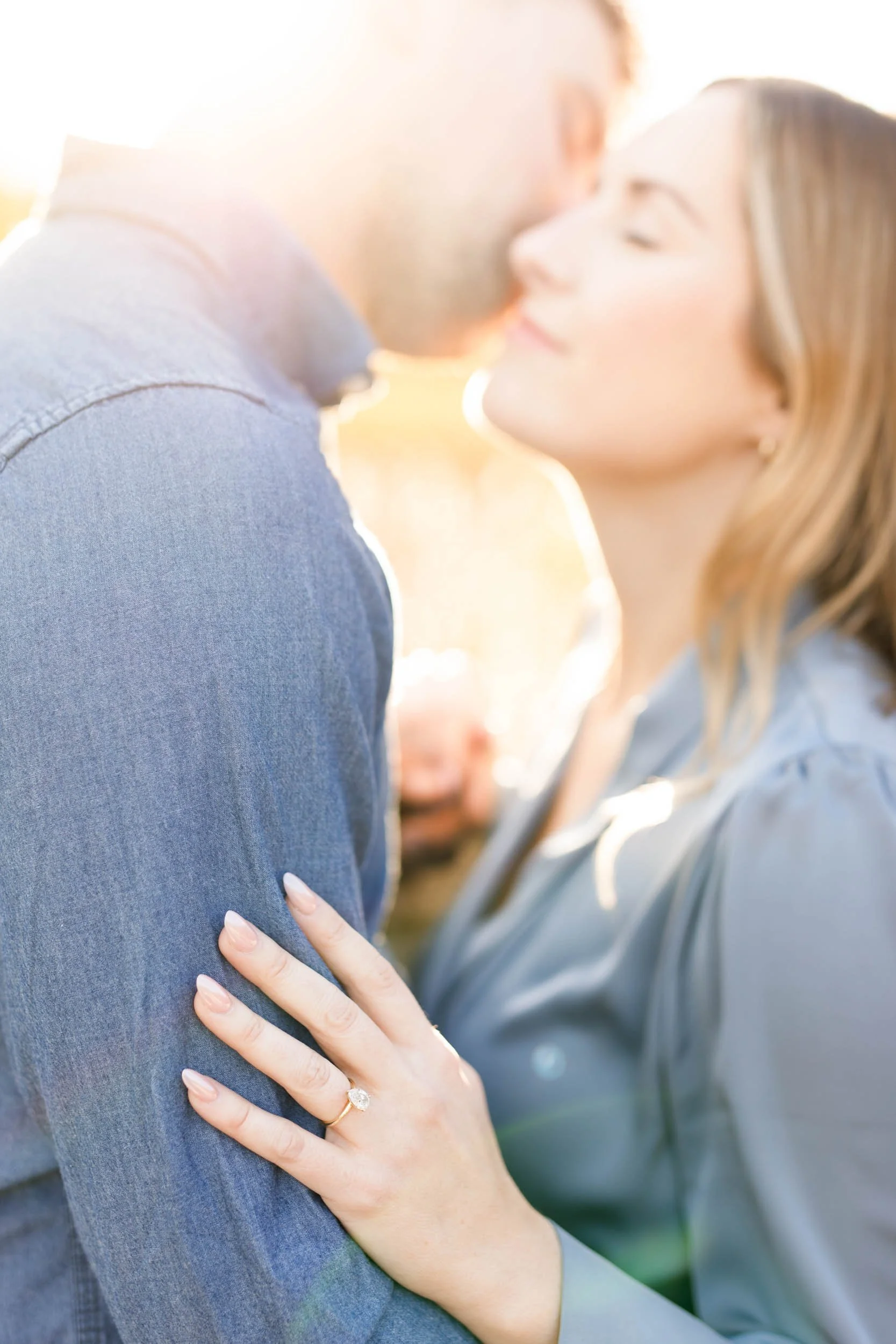 Close-up of engagement ring as couple shares a golden-hour kiss at Grindstone Marsh in Burlington, Ontario