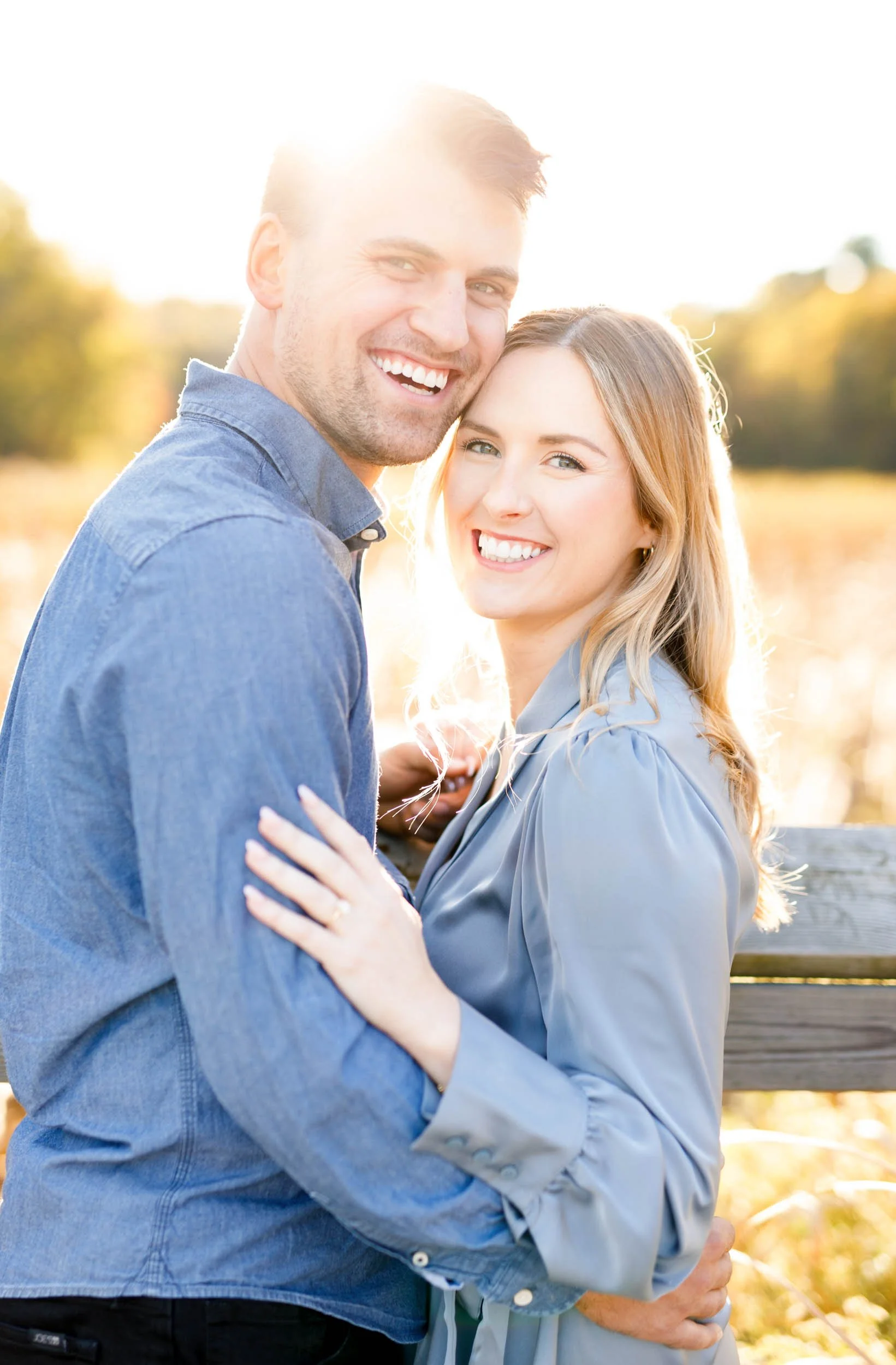 Happy engaged couple posing together at Grindstone Marsh Trail in Burlington Ontario during their fall engagement shoot
