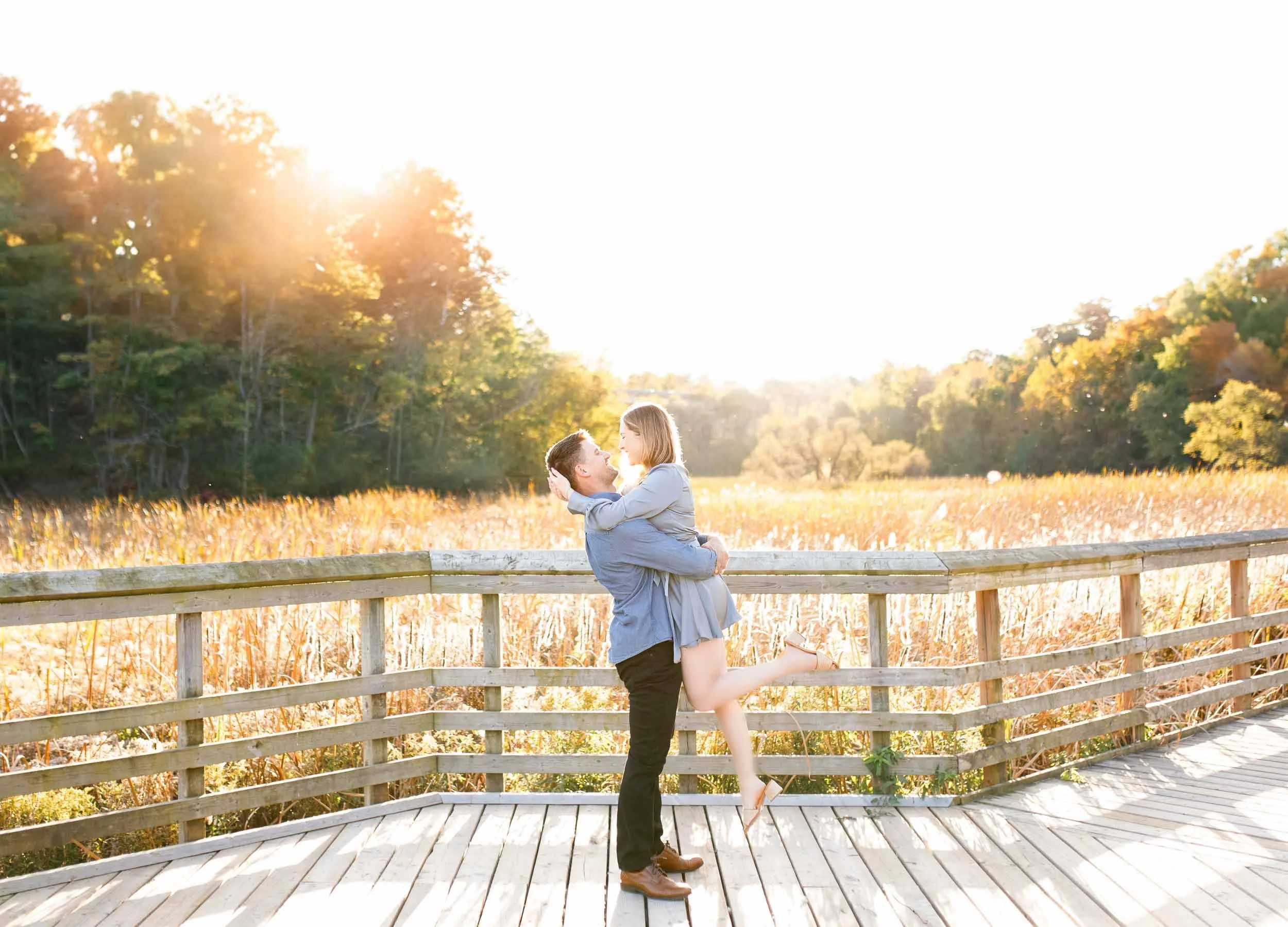 Wide shot of an engaged couple on the boardwalk at Grindstone Marsh Trail in Burlington Ontario at sunset