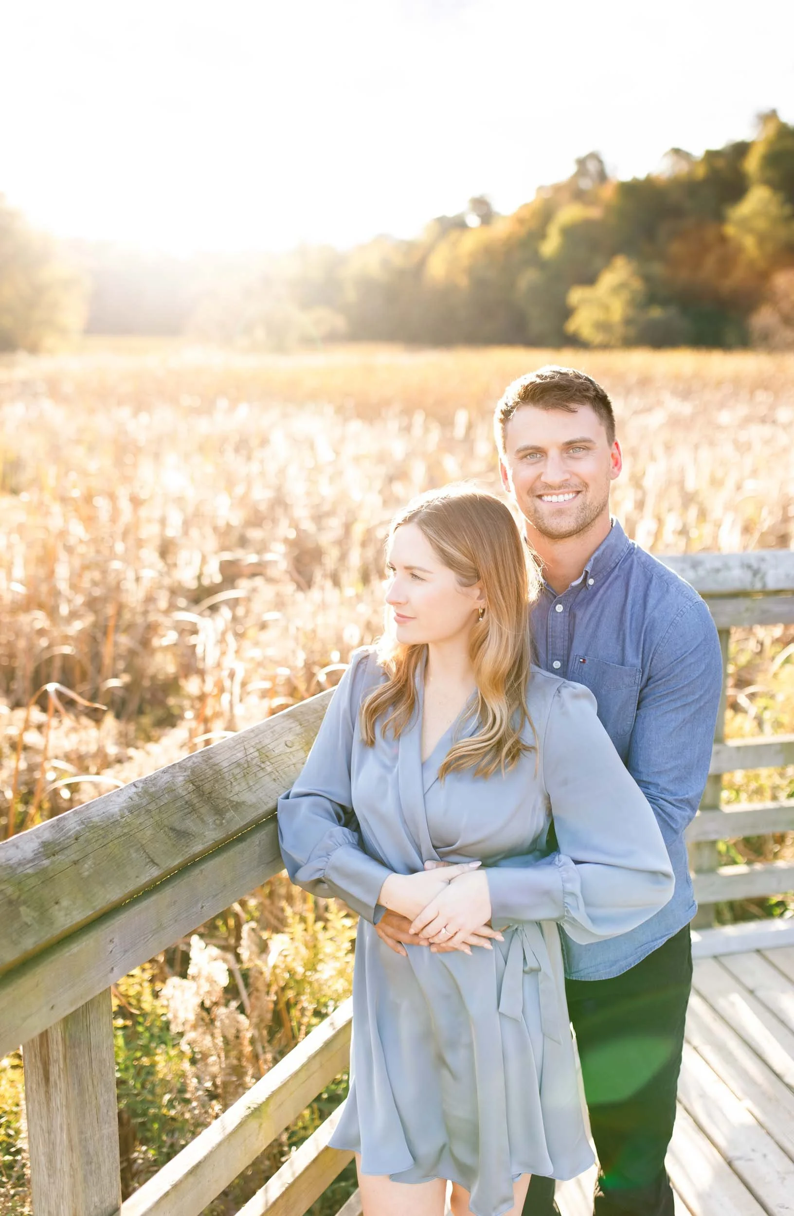 Engaged couple standing together on the boardwalk at Grindstone Marsh Trail in Burlington Ontario during a fall engagement session
