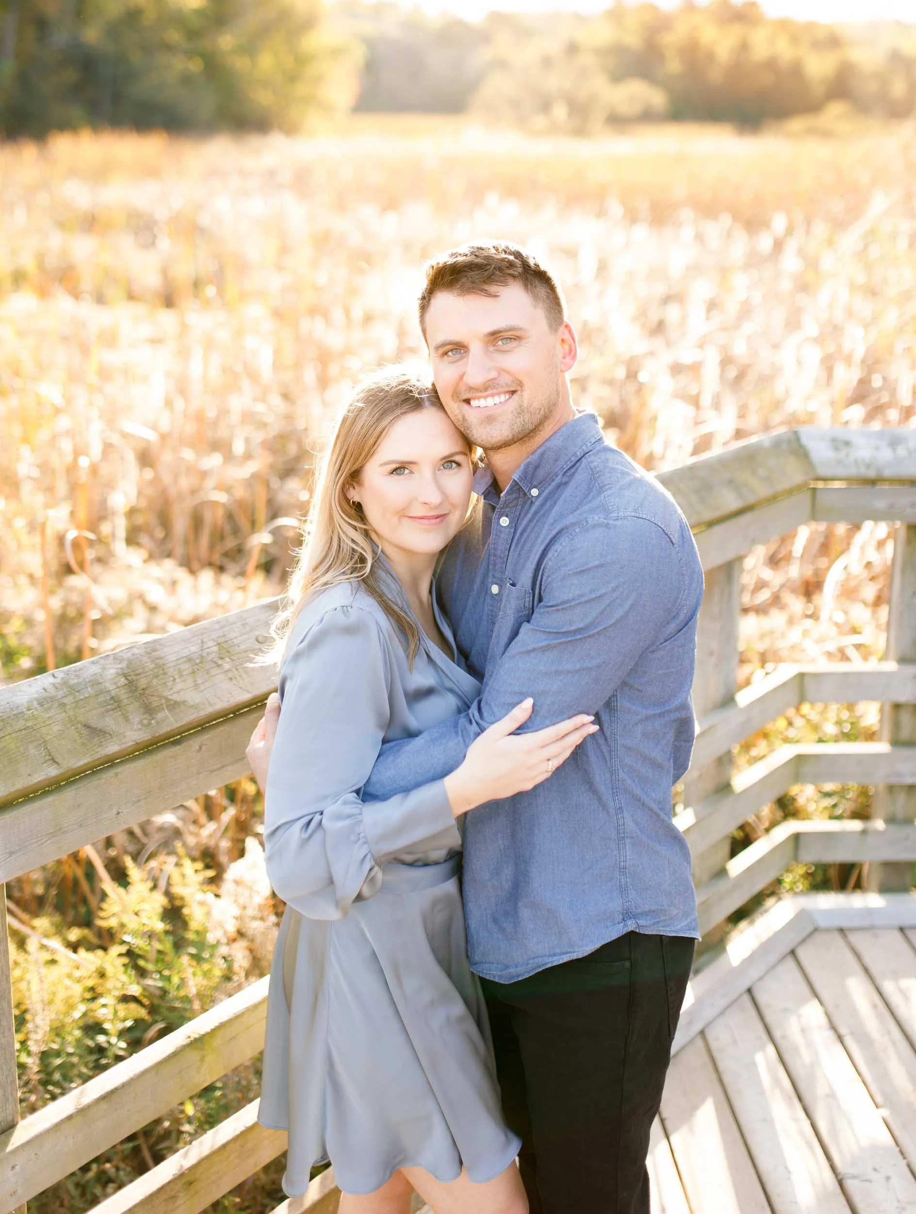 Happy engaged couple posing together on the boardwalk at Grindstone Marsh Trail in Burlington Ontario