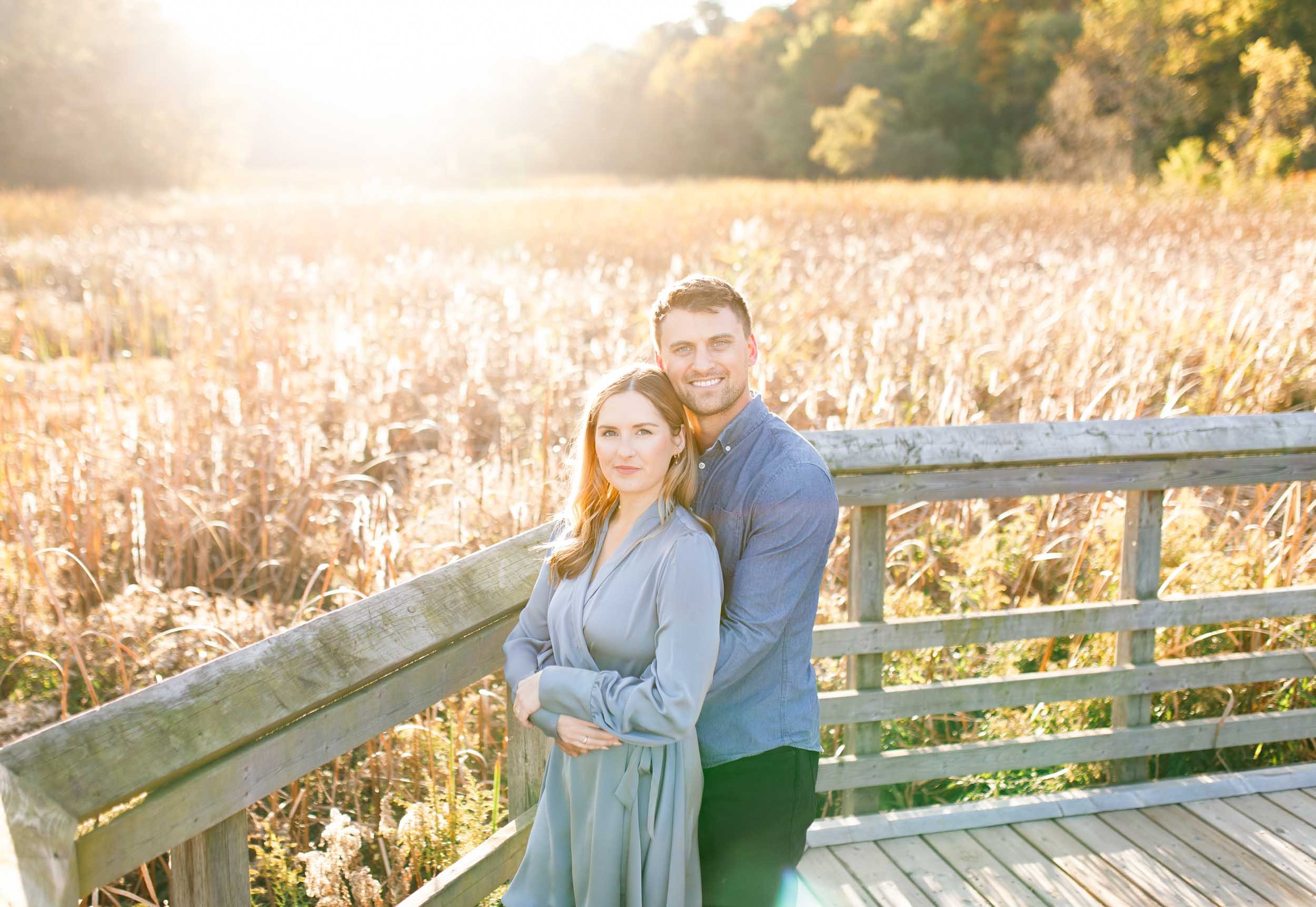 Engaged couple standing close together during a golden hour engagement session at Grindstone Marsh Trail in Burlington Ontario