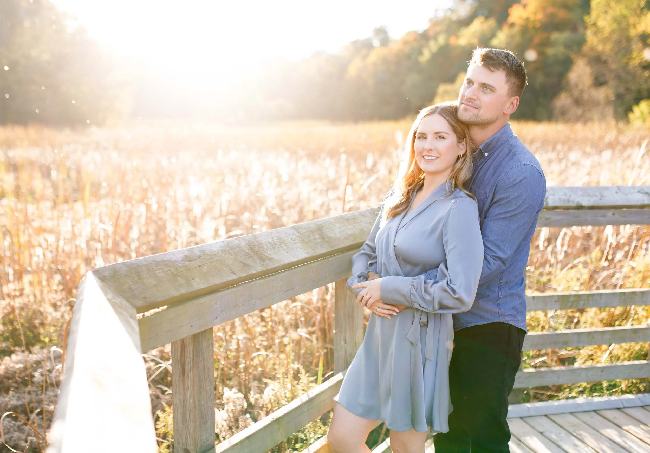 Engagement photo of a couple on the boardwalk at Grindstone Marsh Trail in Burlington Ontario with warm sunset light