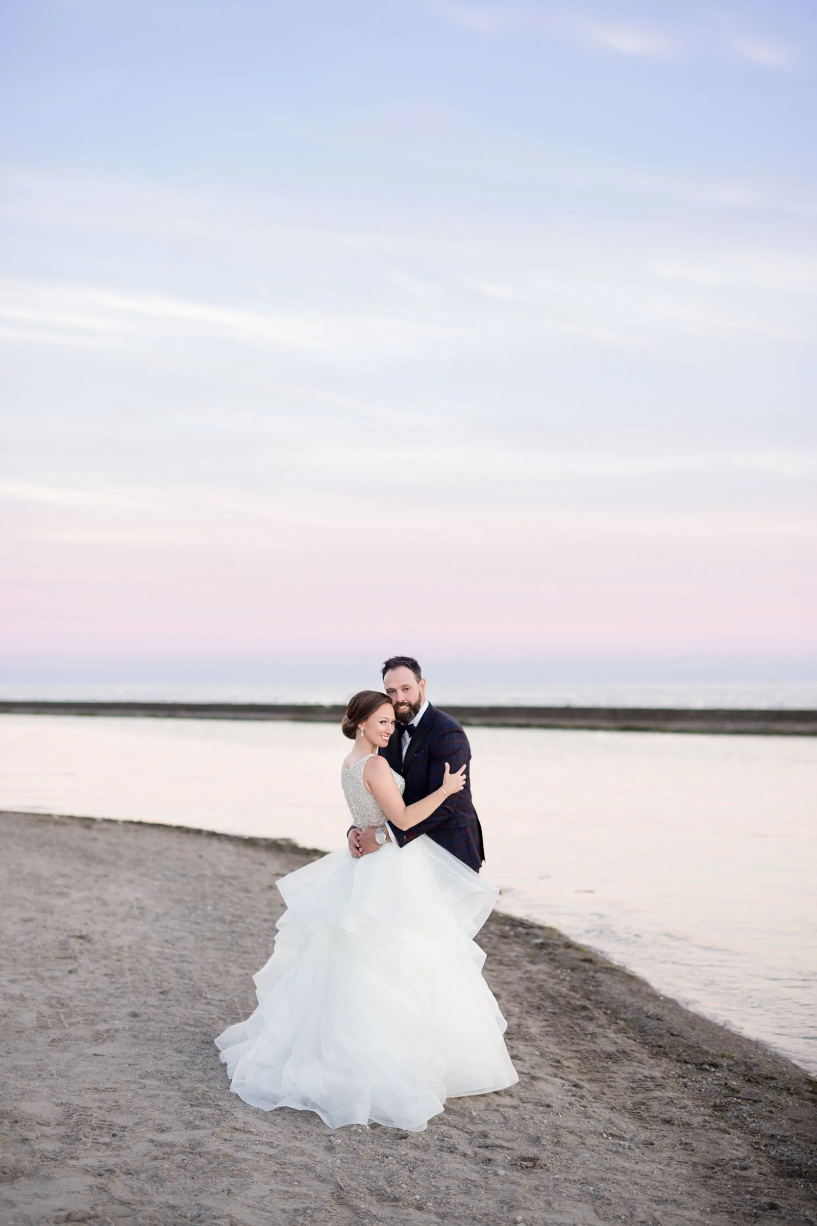 Bride and groom embracing on the beach at sunset along Toronto’s Lakeshore (Copy)