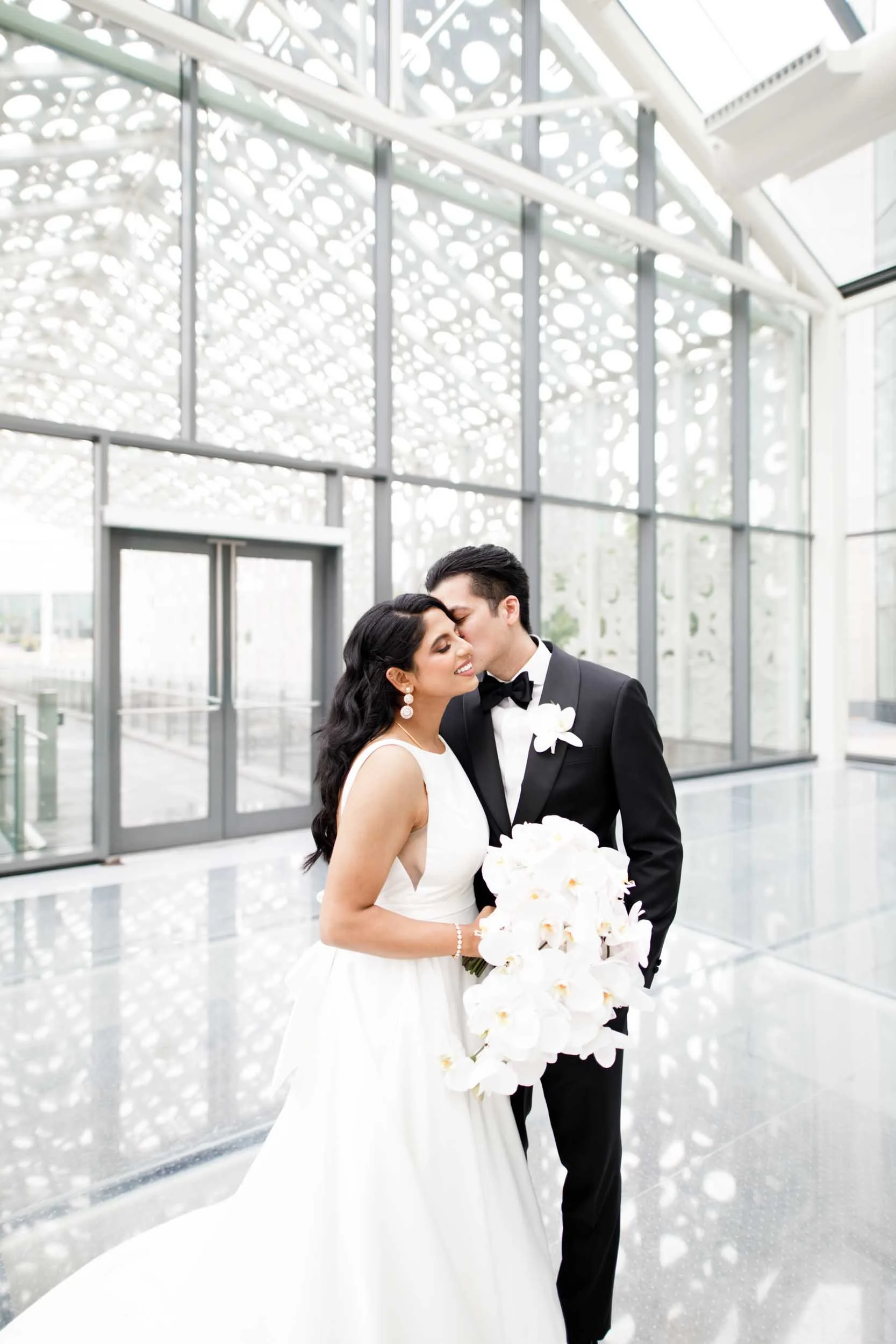 Bride and groom in the Fort Hall at Hotel X Toronto, framed by modern glass architecture (Copy)