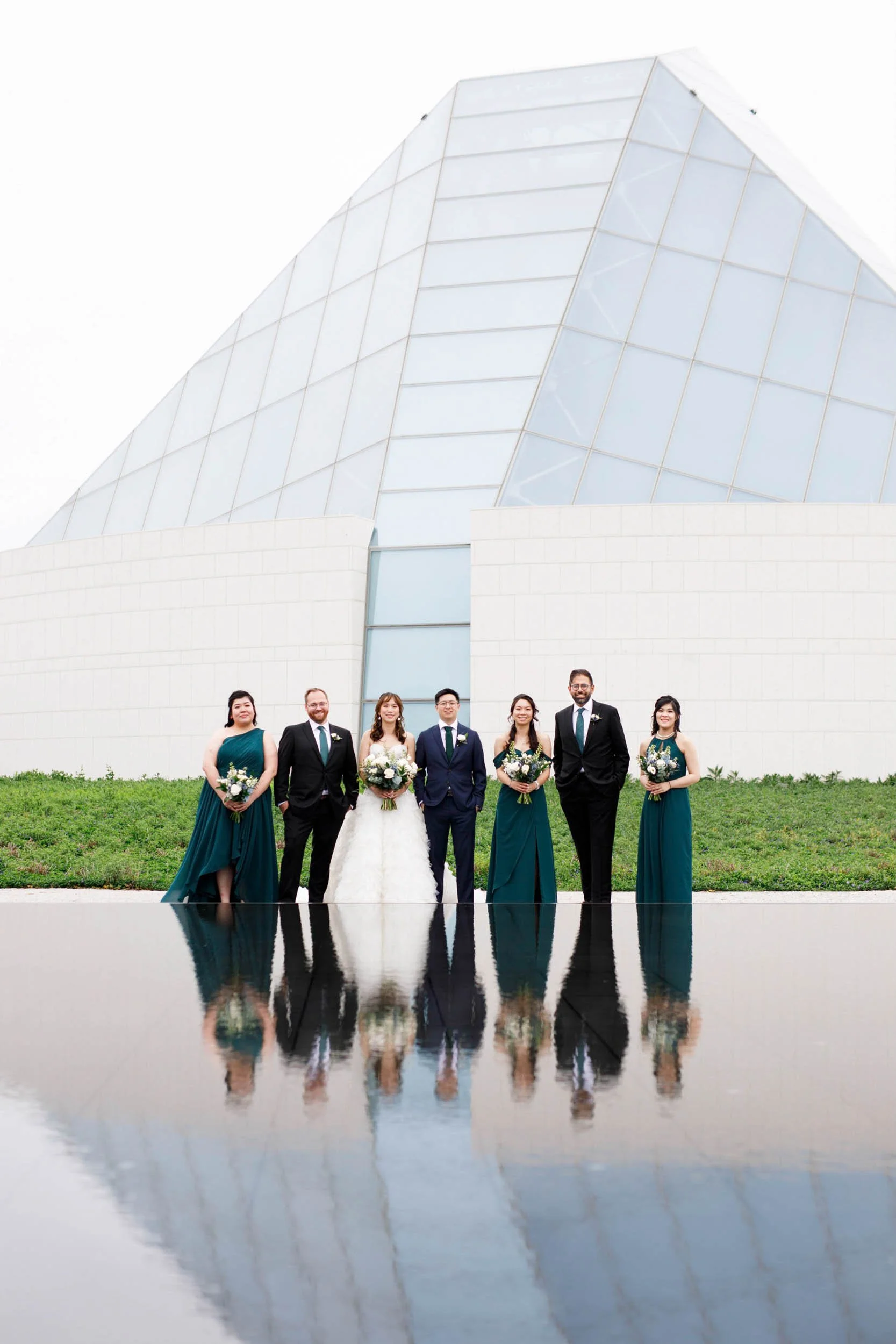 Wedding party standing together with reflections in the infinity pool at the Aga Khan Museum (Copy)