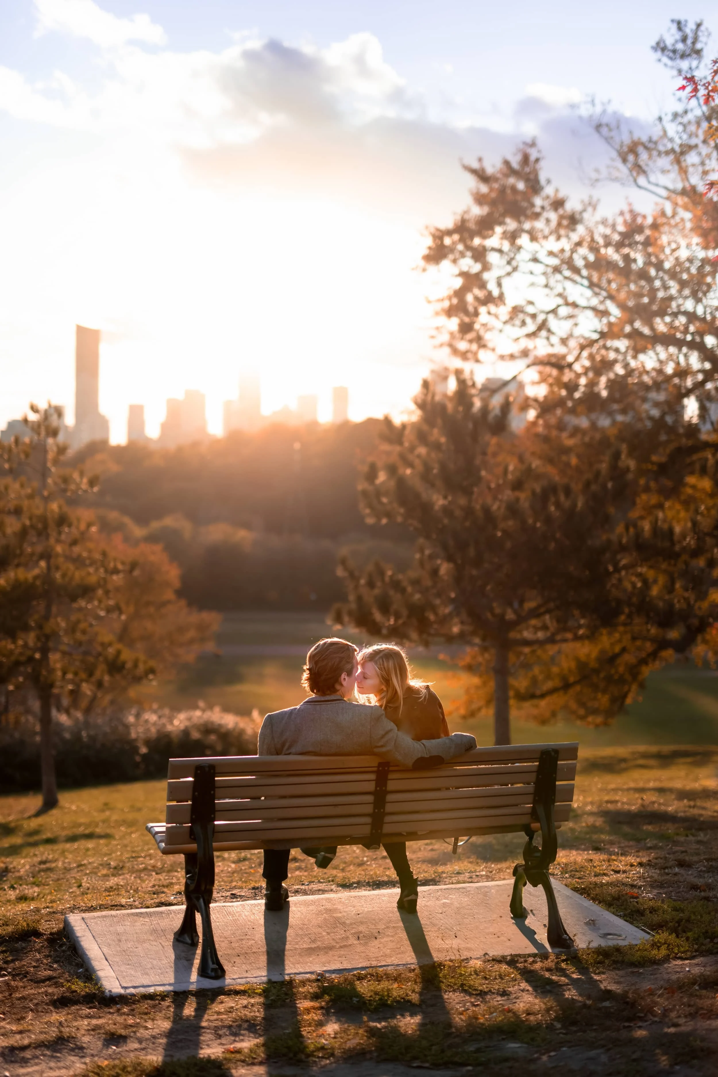 Couple sitting on a sun drenched park bench at sunset overlooking Toronto from Riverdale Park (Copy)